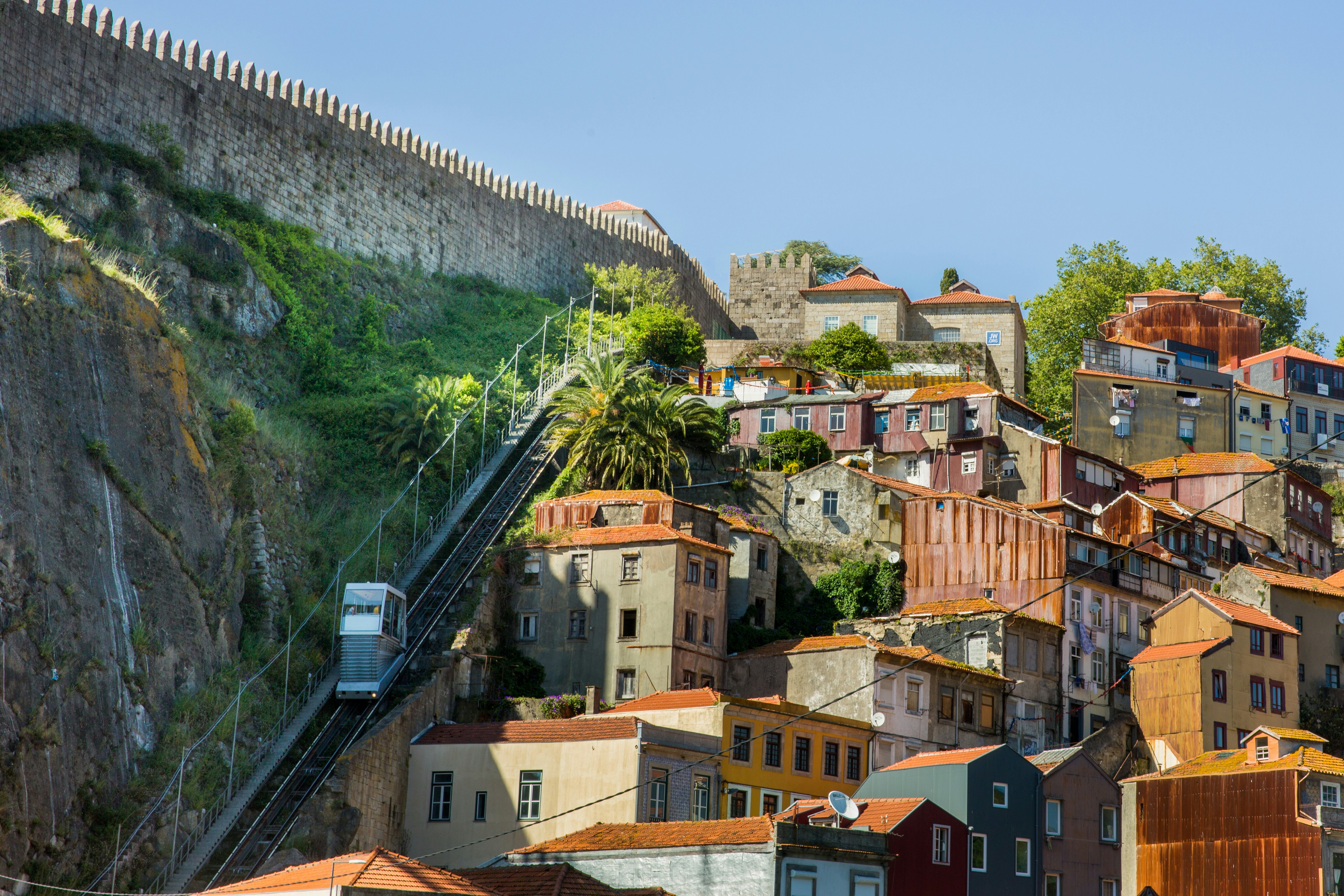 A funicular car climbs a hillside next to red-roofed buidlings