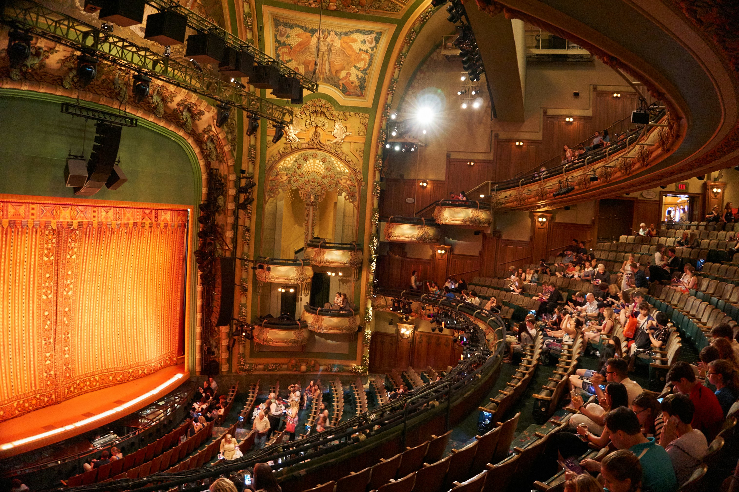 A theater filling up with people taking their seats to watch a stage show