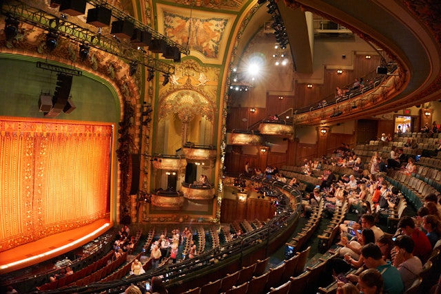A theater filling up with people taking their seats to watch a stage show