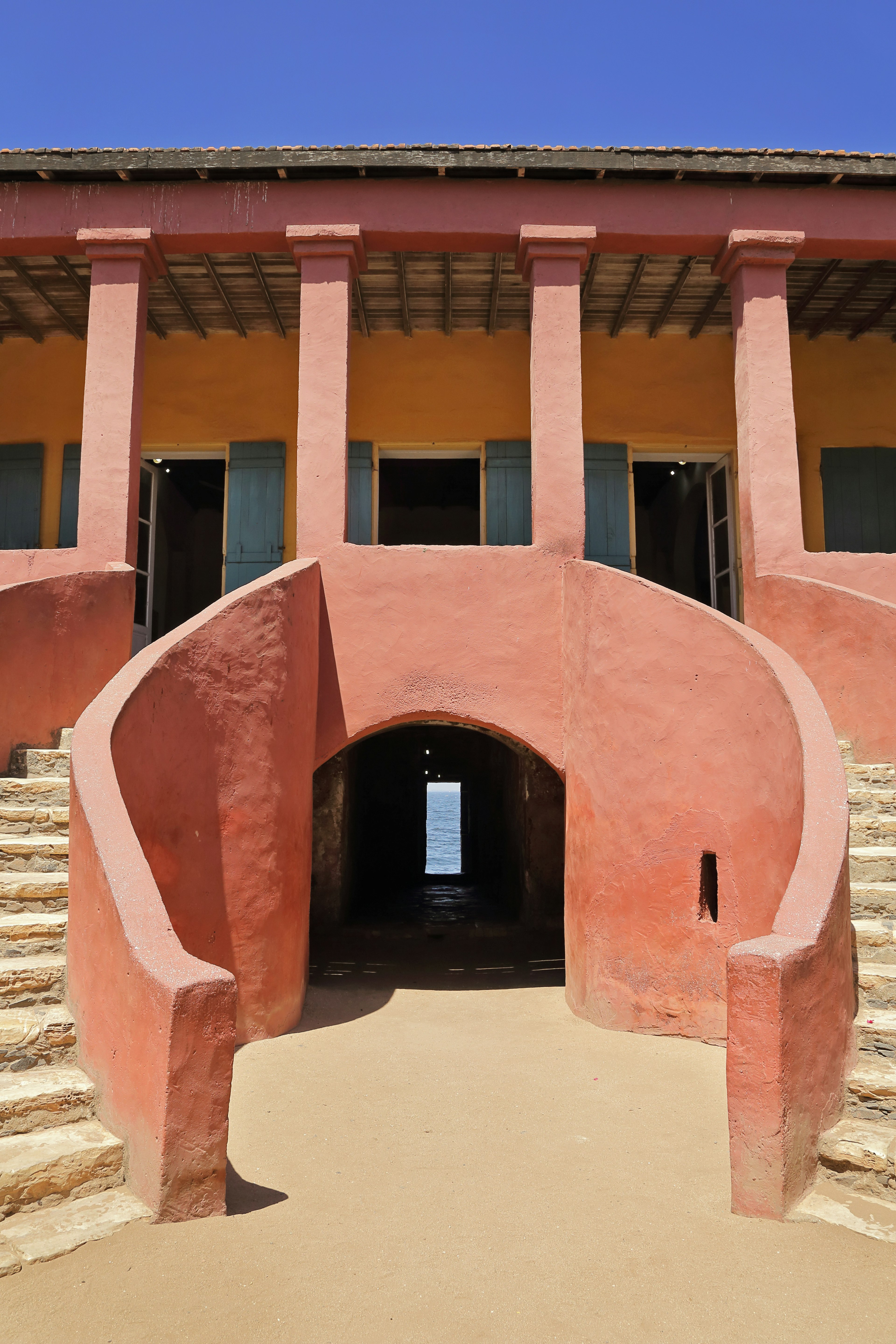 Taken from La Maison des Esclaves courtyard on Gorée, this image looks up the twin, curving staircases and through a dark passage between the stairs. A small opening appears in the darkness