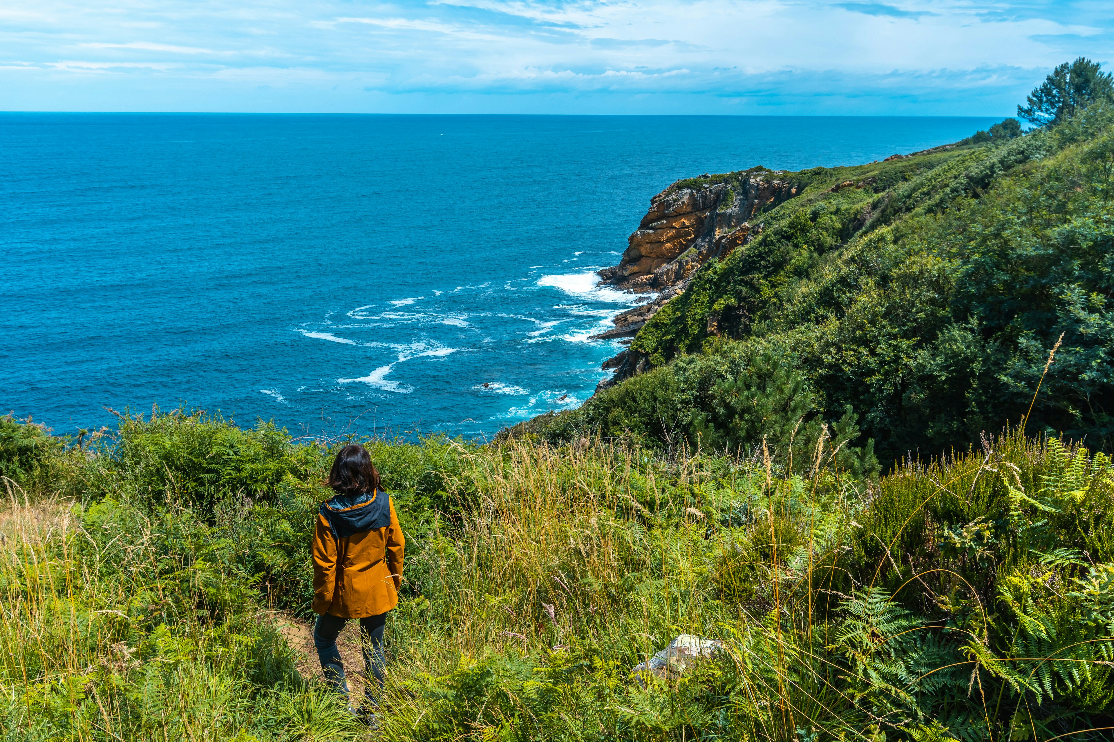 A hiker looks at the sea from a trail on Monte Ulia, San Sebastian