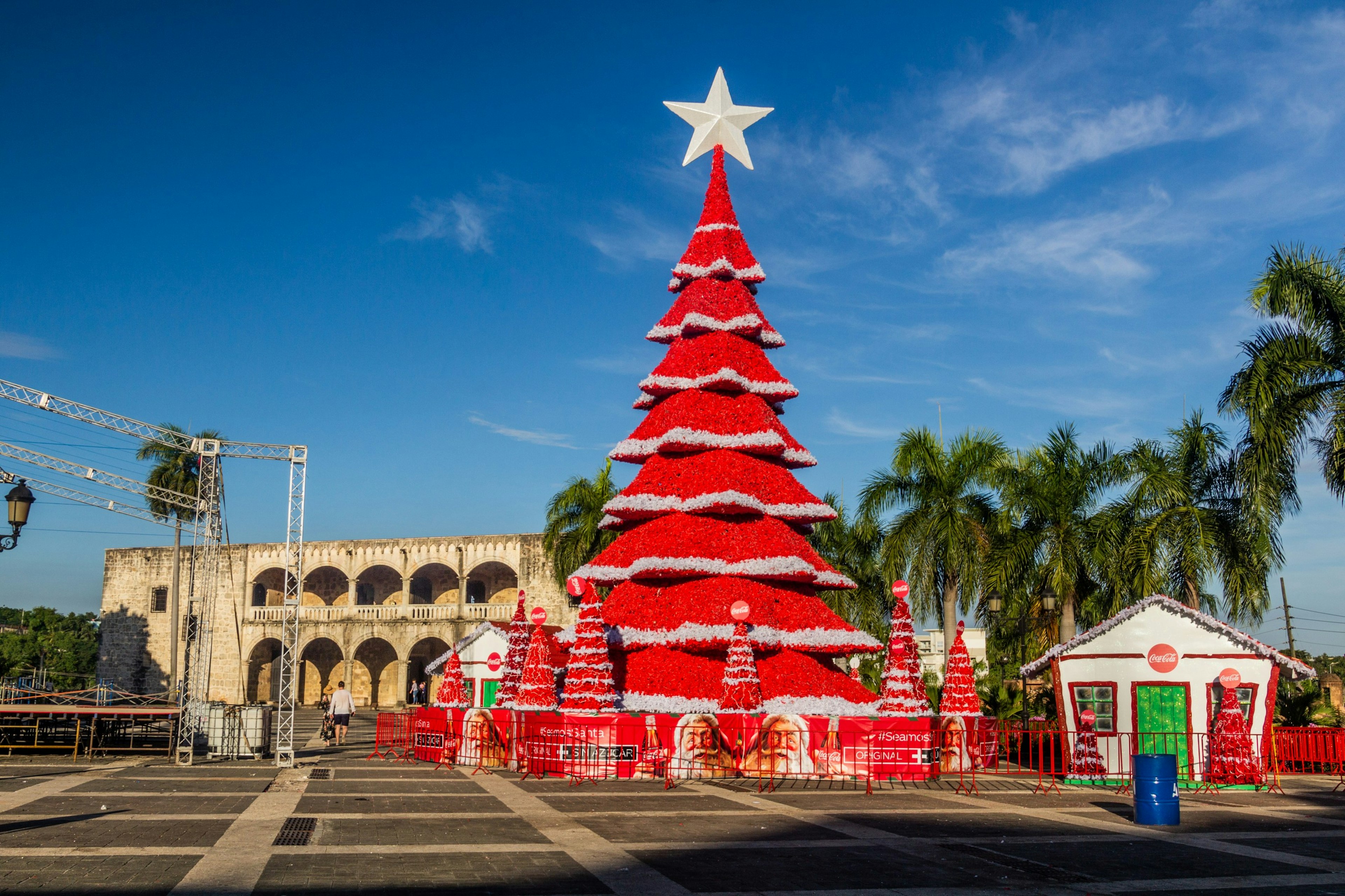 A red Christmas tree stands by palm trees and the historic Alcazar de Colón, Santo Domingo, Dominican Republic