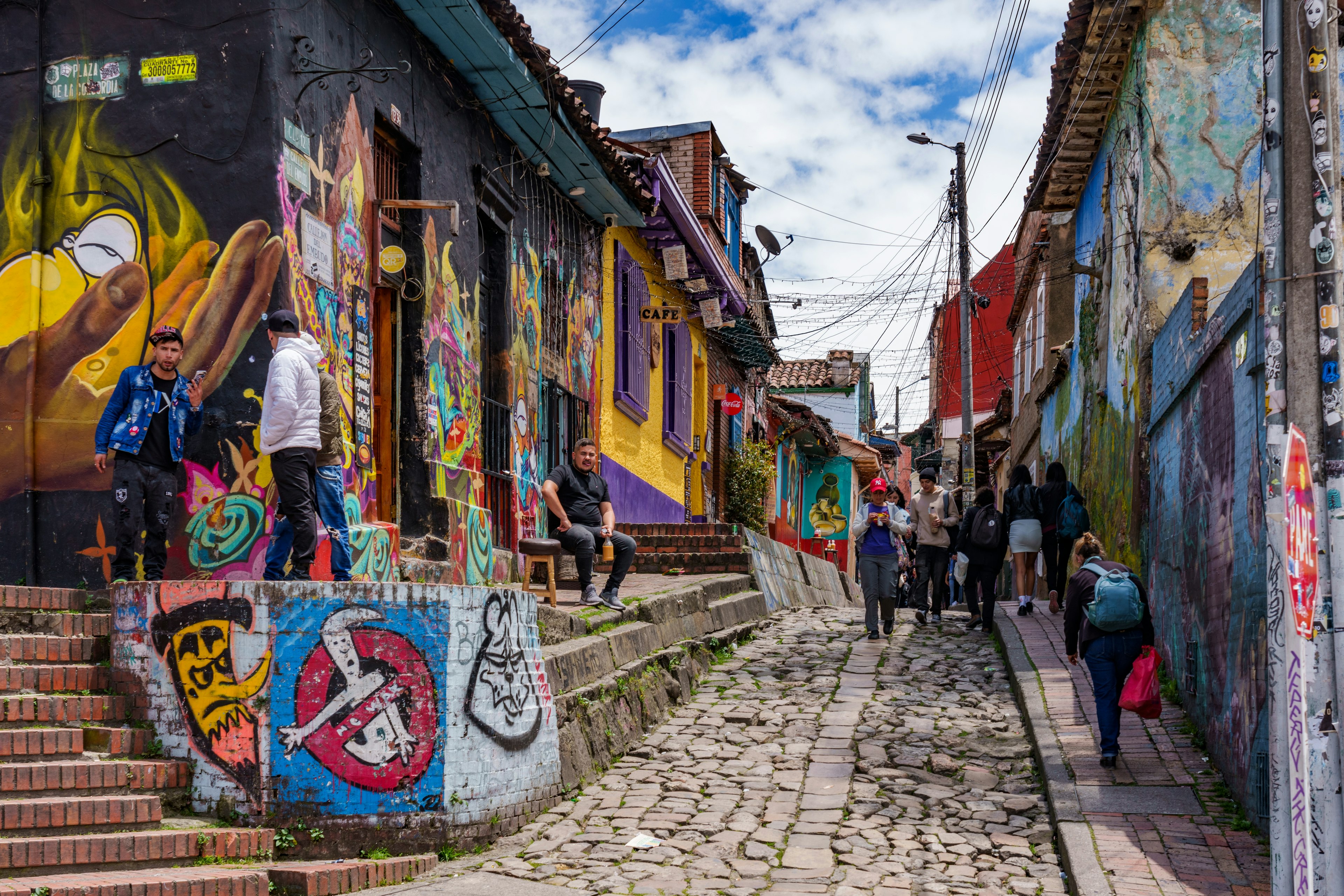 People walk in a narrow cobbled street with nearly every wall painted in colorful murals