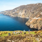 Sliabh Liag, Ireland - 04.21.2024: Group of hikers on footpath into mountains, beautiful cliff and ocean nature background. Travel and tourism industry. Warm sunny day., License Type: media, Download Time: 2024-11-26T12:04:08.000Z, User: clairenaylor, Editorial: true, purchase_order: 65050 - Digital Destinations and Articles, job: Online editorial, client: Ireland best things to do, other: Claire Naylor