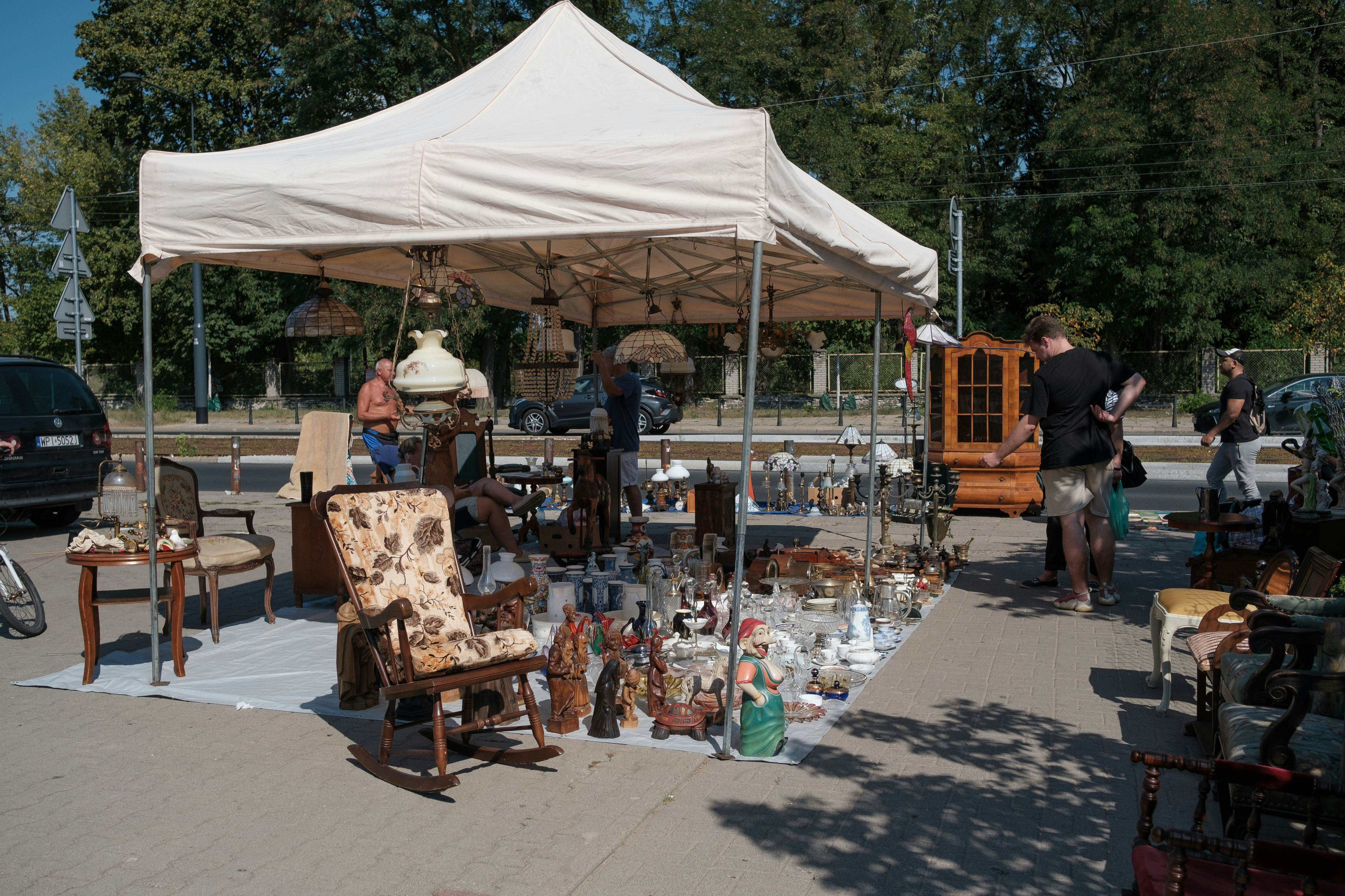 A pop-up tent provides shad to a market trader who has set out all their household goods for sale