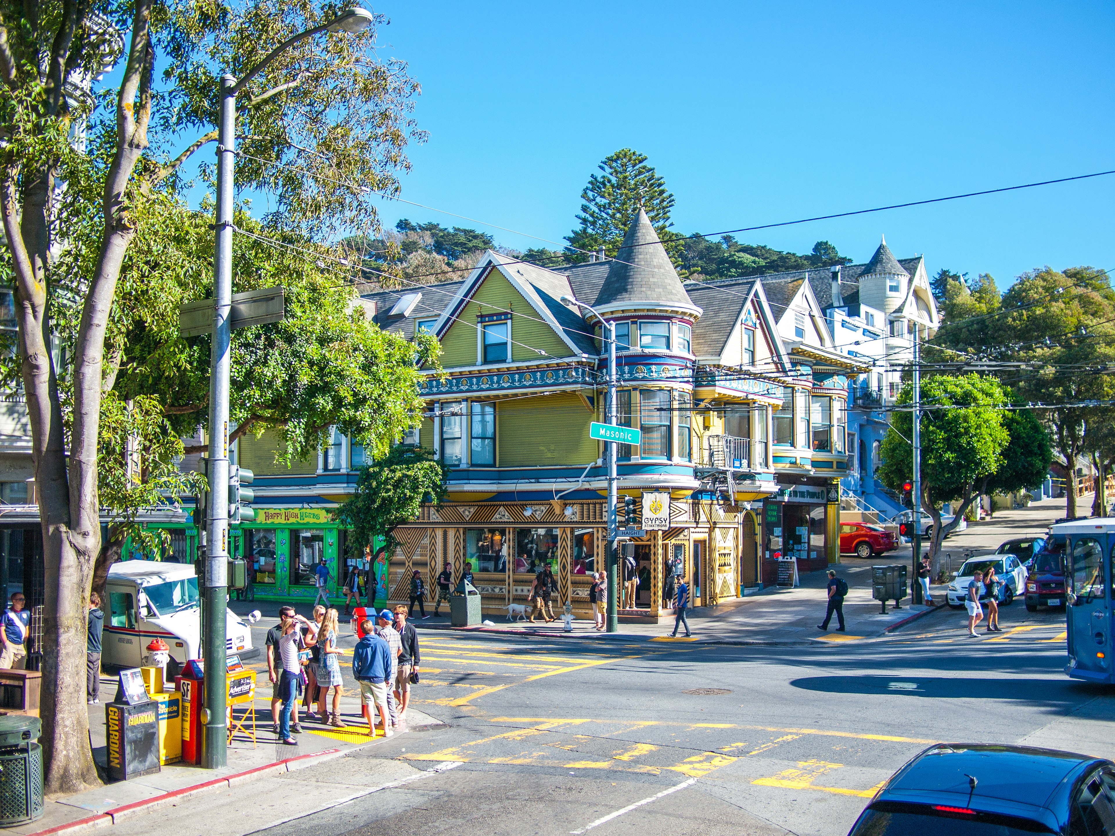 Crowds walk by Victorian-style buildings in the Haight-Ashbury neighborhood in San Francisco, California, USA