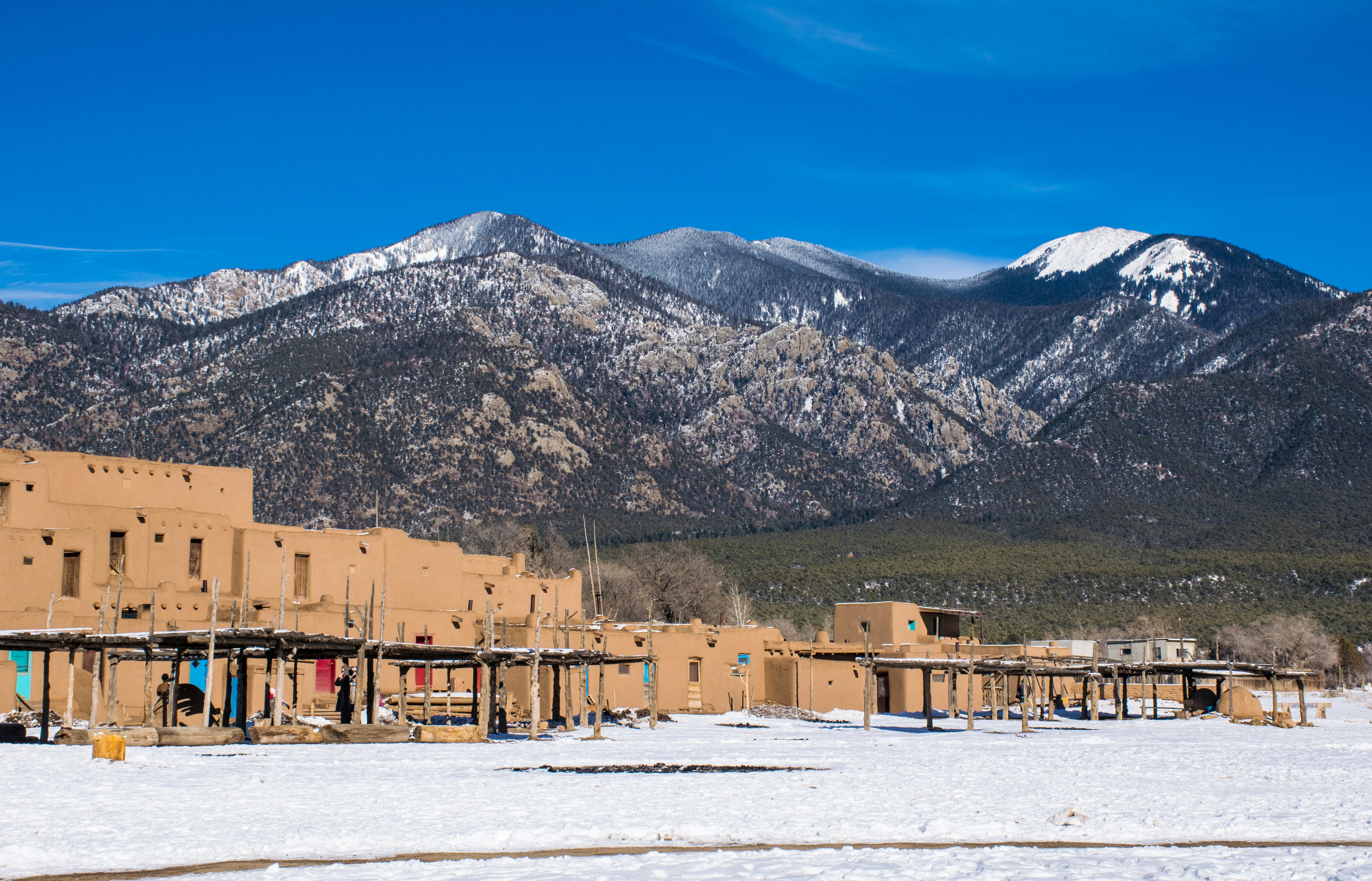 Low-rise red square buildings on a plateau at the foot of a snow-capped mountain range