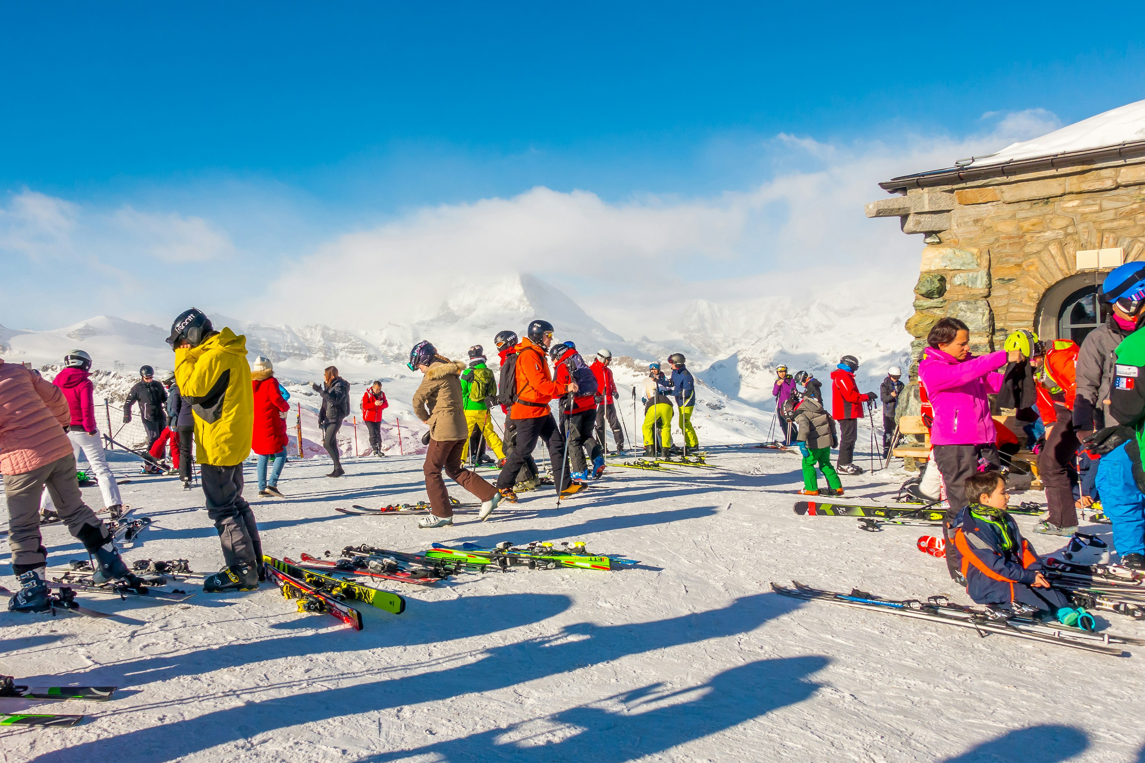 Skiers in colourful jackets prepare to descend a run.