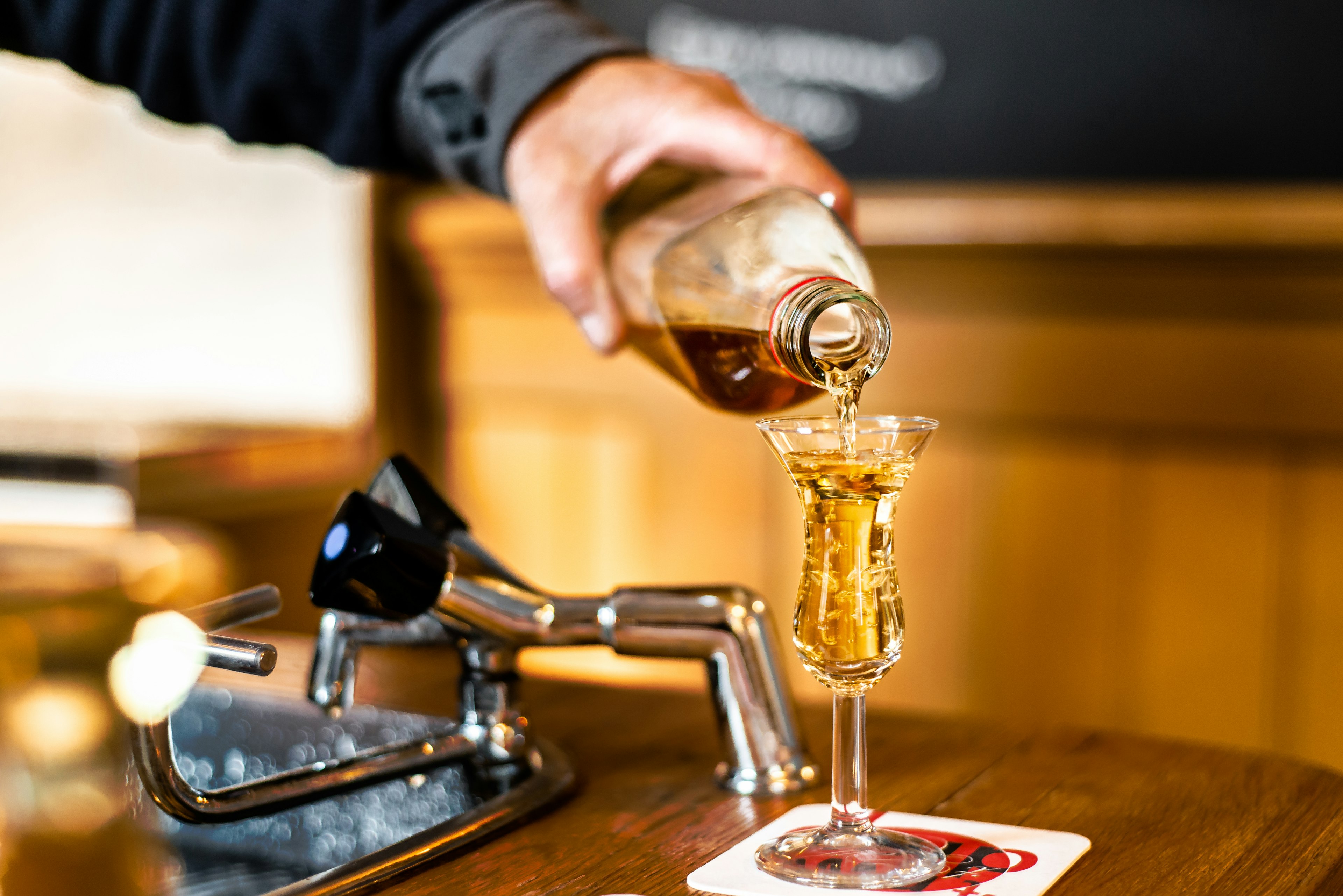 A bartender pours jenever/genever into a tulip shot glass.