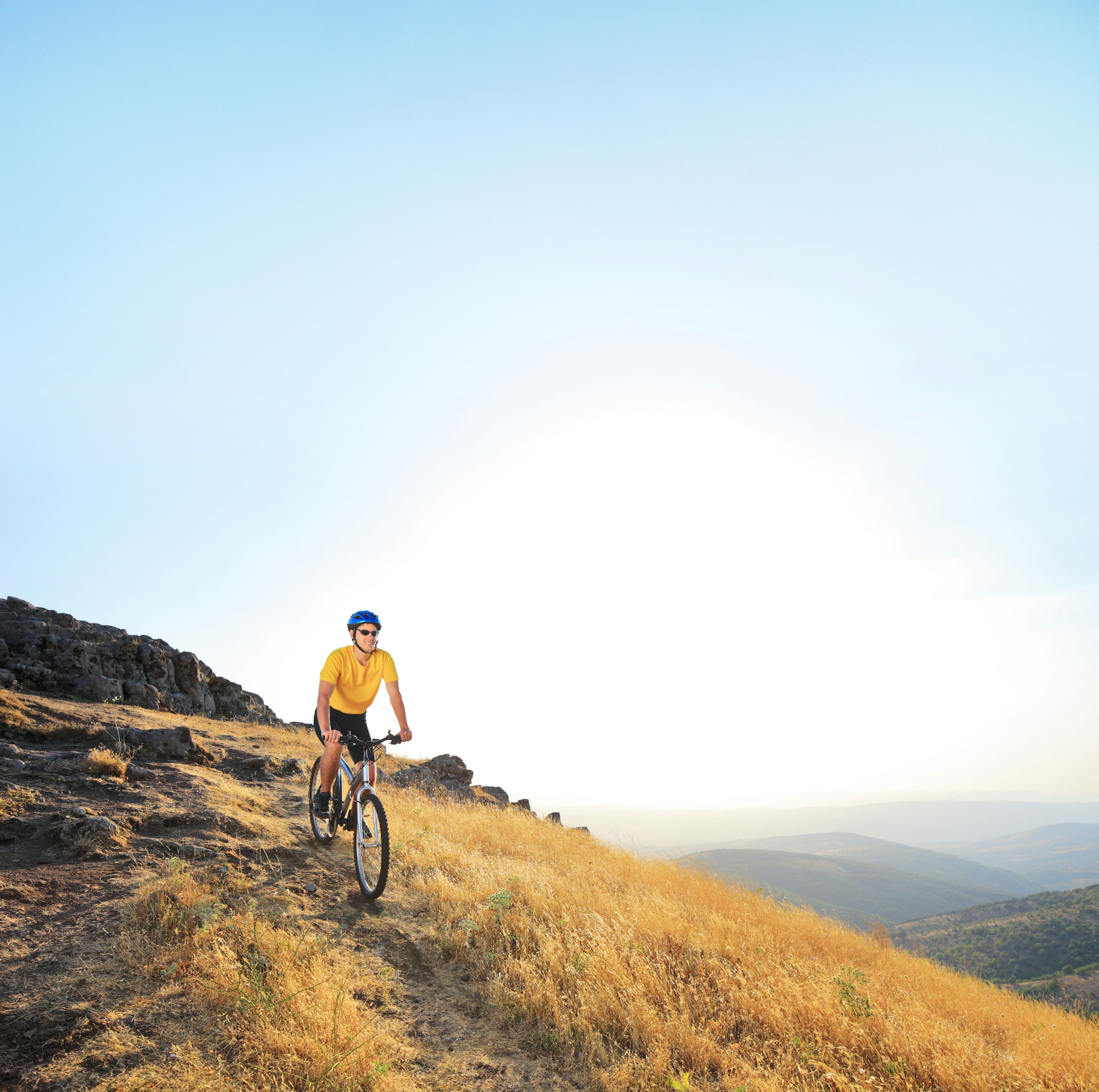 Male riding a mountain bike down hill during sunset.