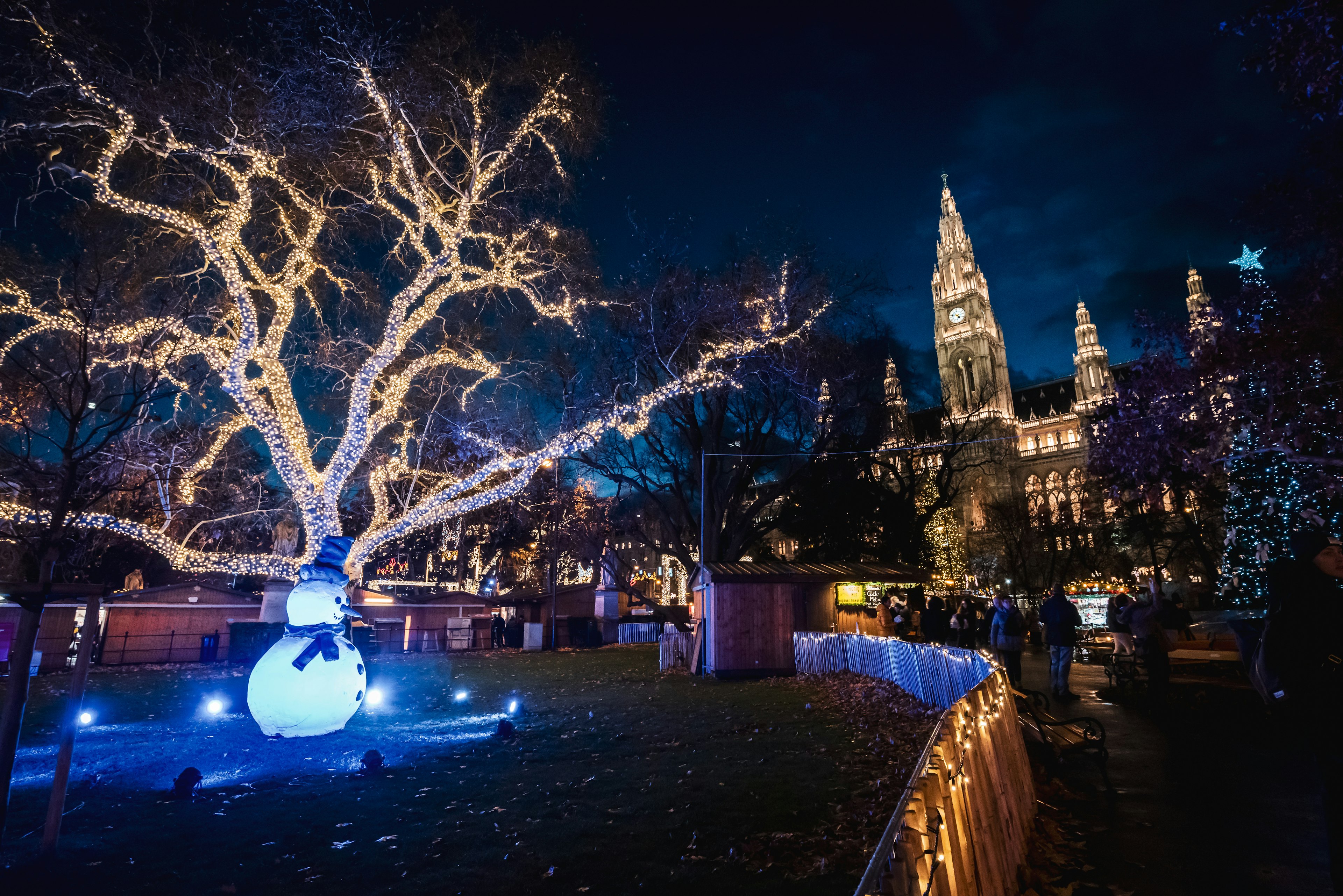 Illuminated snowman and tree at the Christmas markets in Rathausplatz at night.