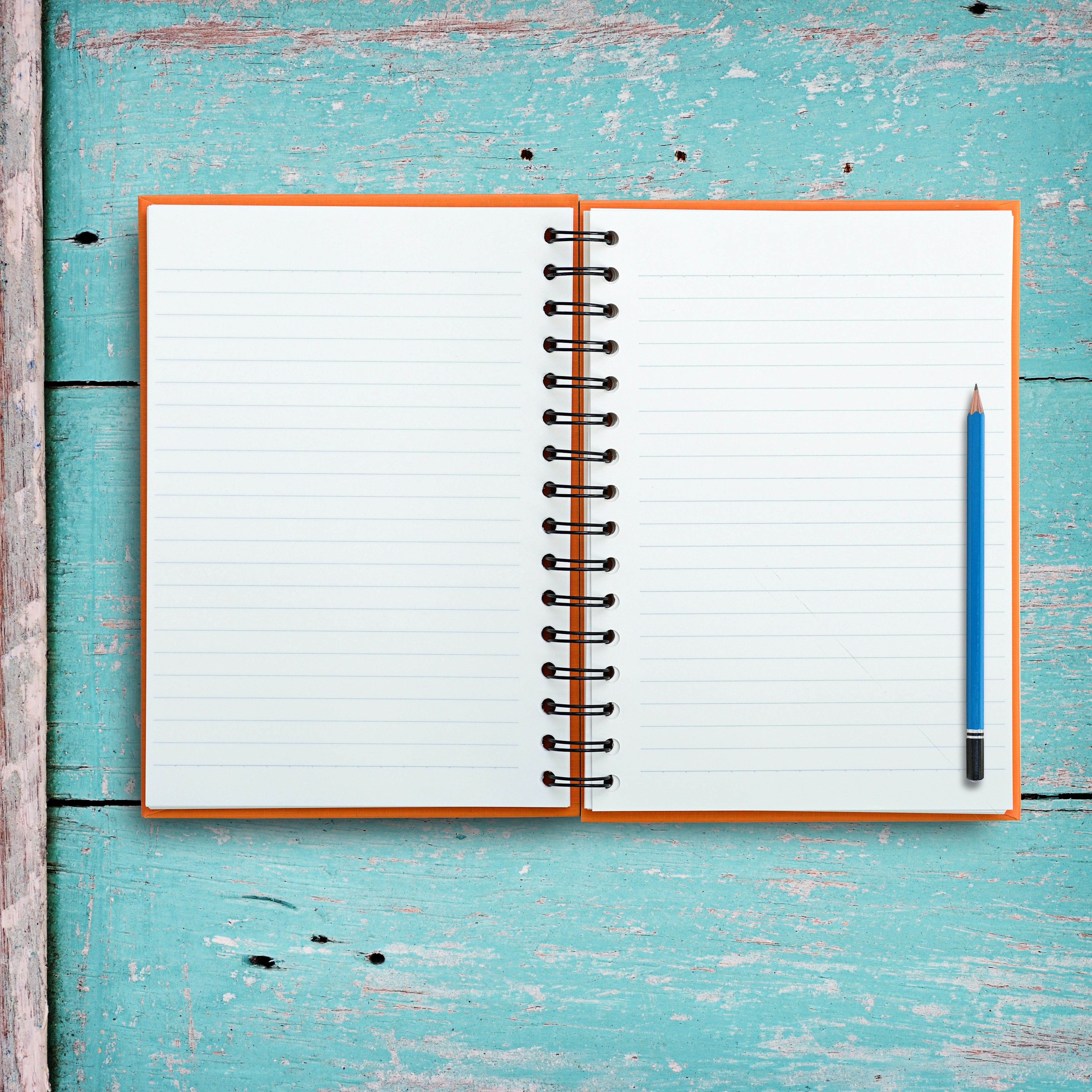 Open notebook with pencil on grunge wood background.