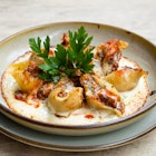 Close-up of fresh homemade Italian stuffed pasta conchiglioni with beef ragout bolognese, cream cheese, tomato sauce and parsley.