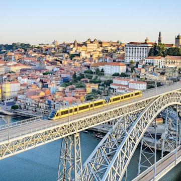 A metro train crosses the Dom Luiz bridge with the historic city of Porto beyond.
148234274
RFC, Shutterstock, day, city, blue, view, tram, port, porto, douro, ponte, river, metro, sunny, oporto, center, bridge, railway, history, downtown, daylight, landmark, building, portugal, historic, cityscape, horizontal, architecture, dom luiz, old city, Aerial View, Arch, Architecture, Bridge, Building, Cityscape, Outdoors, Railway, Train, Transportation, Urban, Vehicle
A metro train crosses the Dom Luiz bridge with the historic city of Porto beyond.