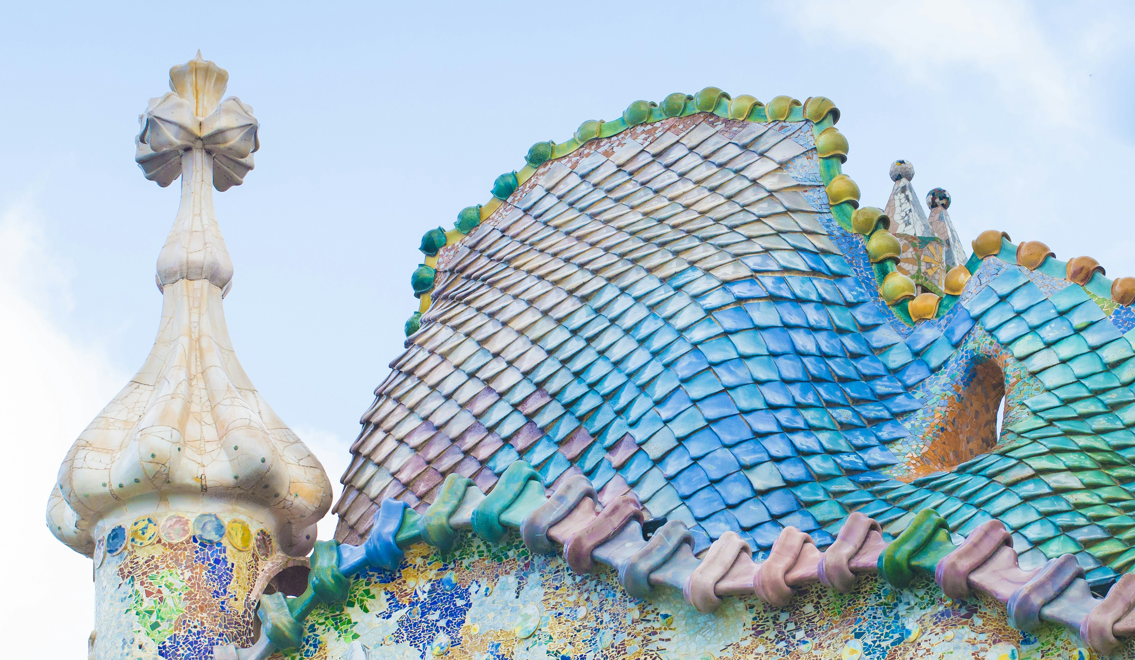 A close-up of shimmering tiles in blues, greens, pinks and yellows, creating an effect like fish scales or dragon skin