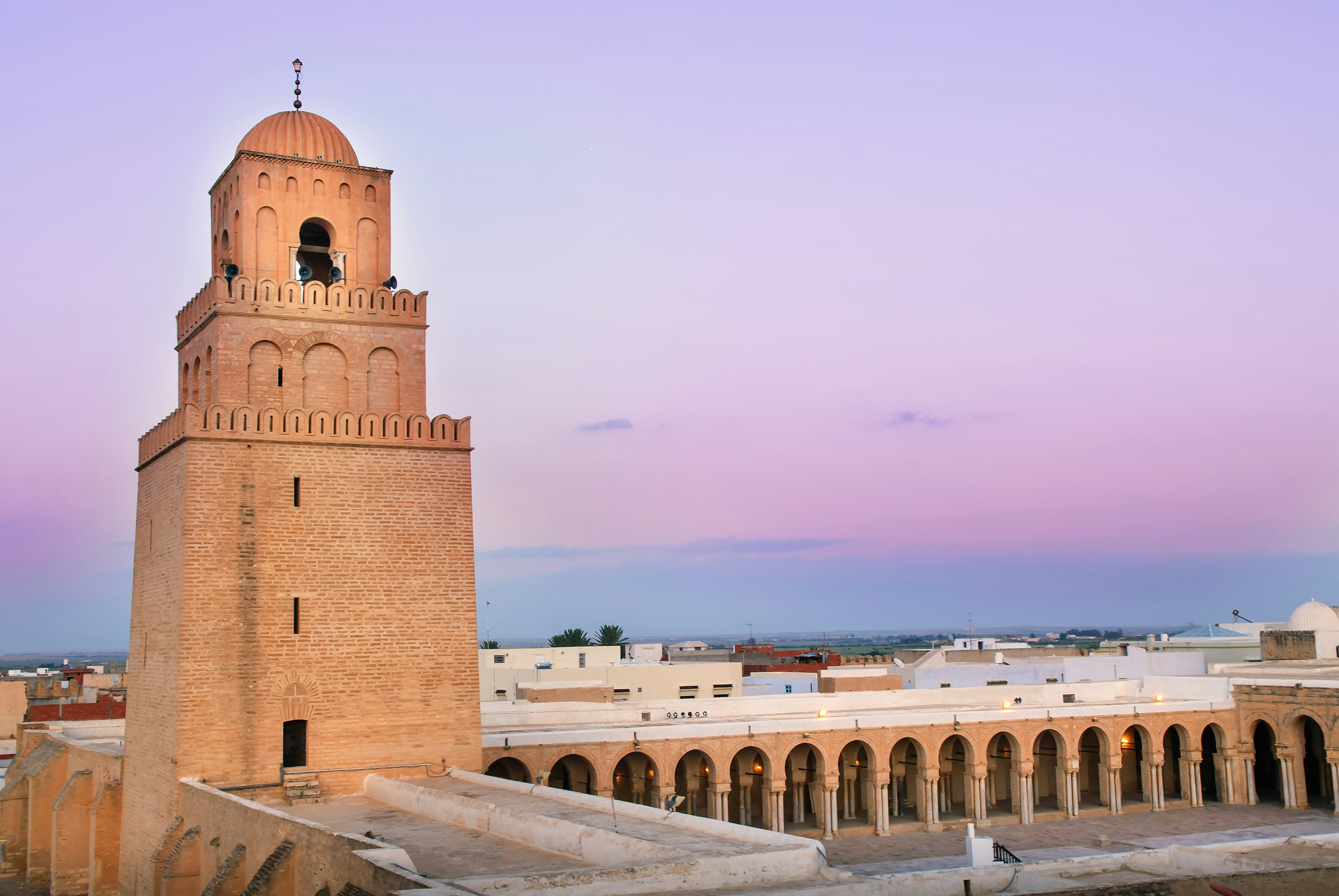 A tower of the Great Mosque of Kairouan in low light.