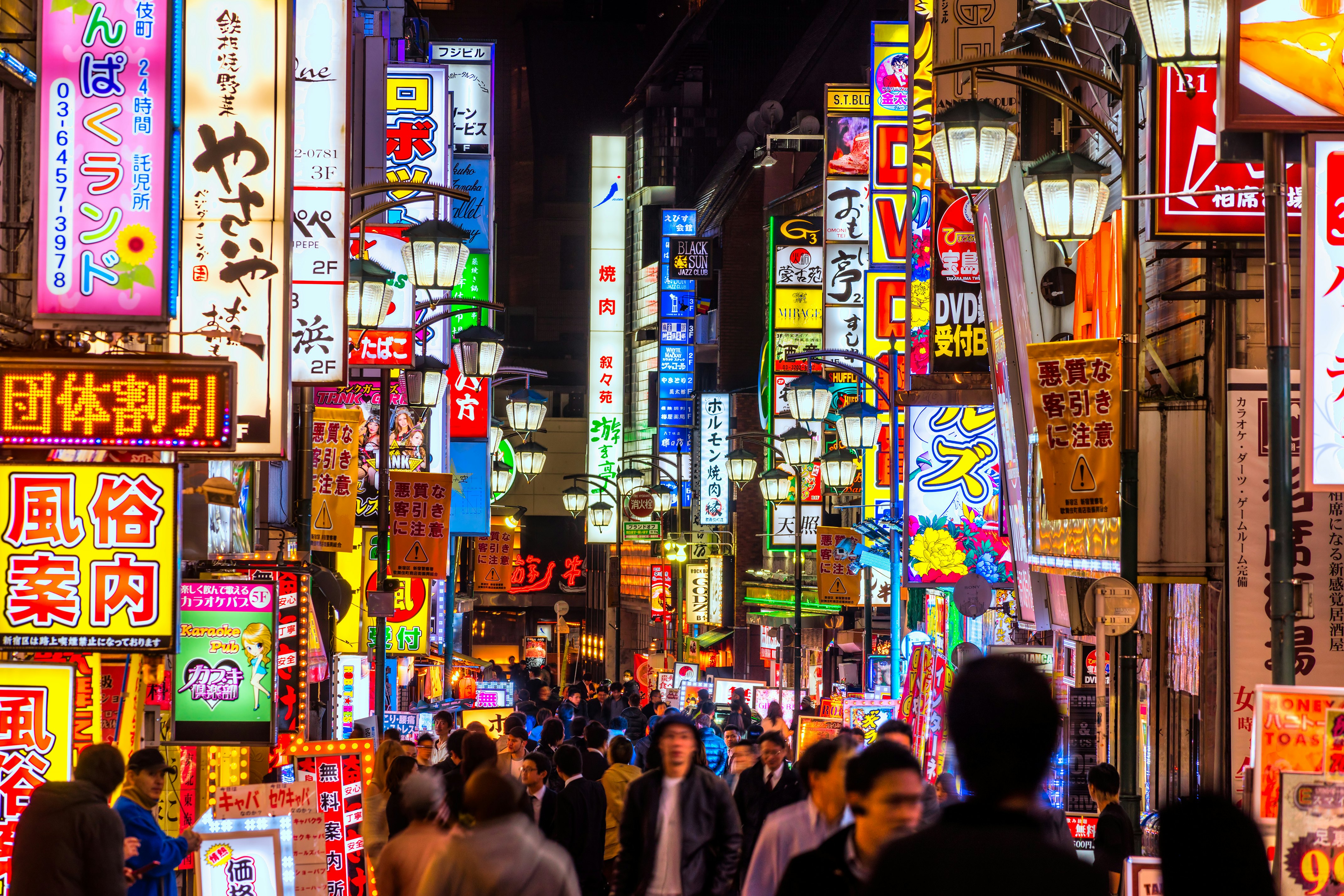 A busy street lined with neon signs lit up at night