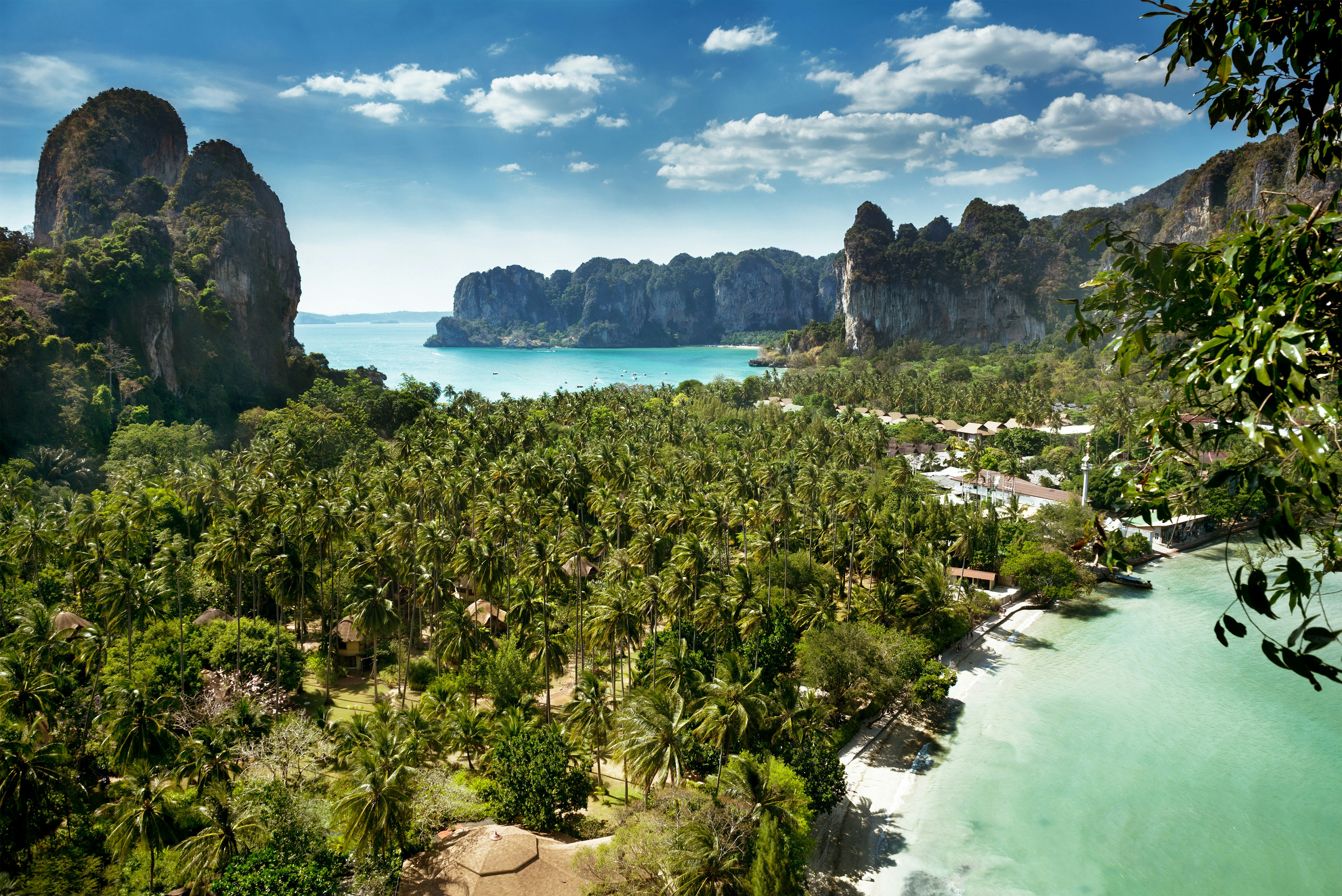 Palm trees cover a narrow section of land between two shores on a rocky island