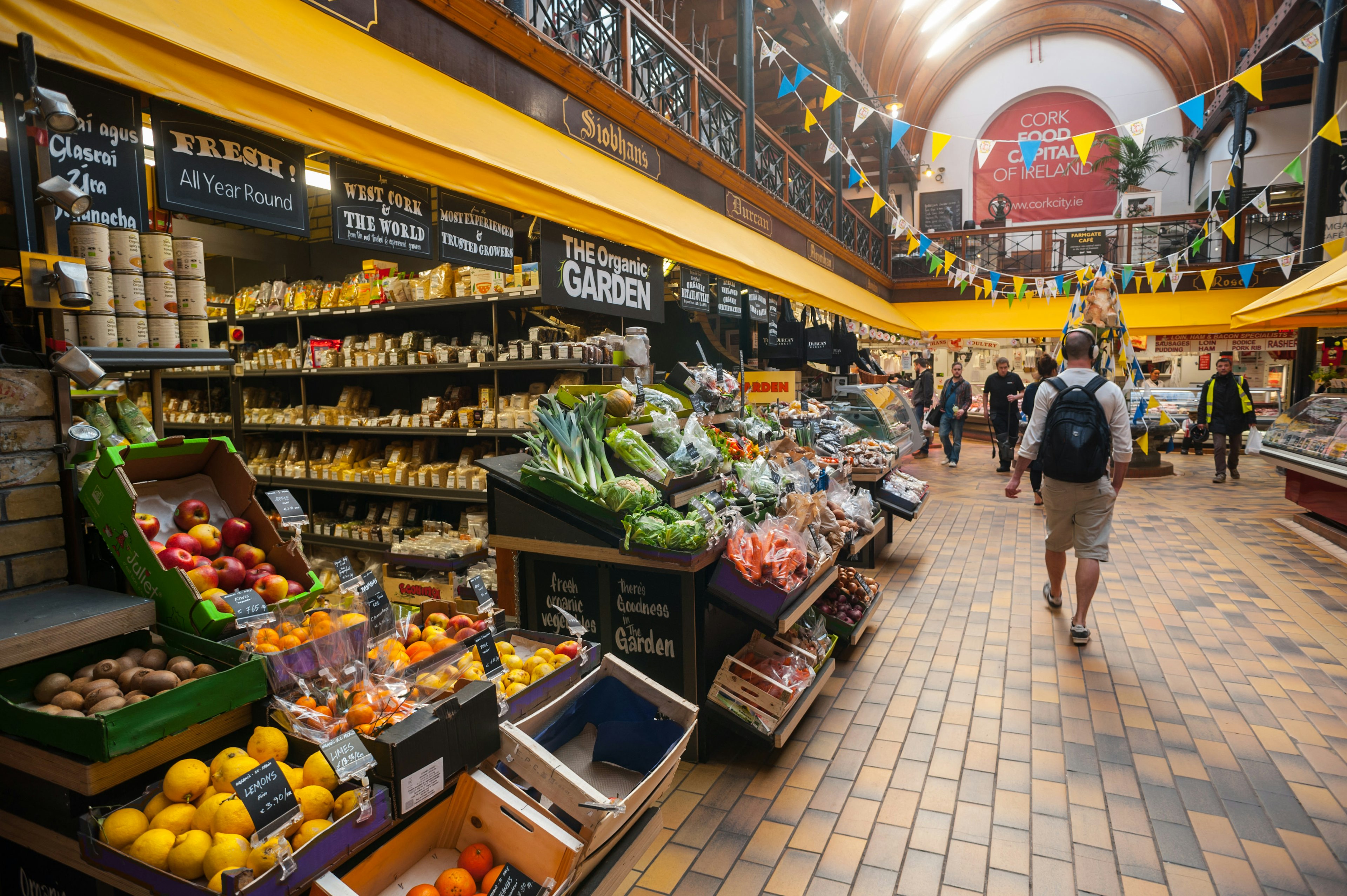 A covered market place with colorful fresh fruit and vegetable stalls