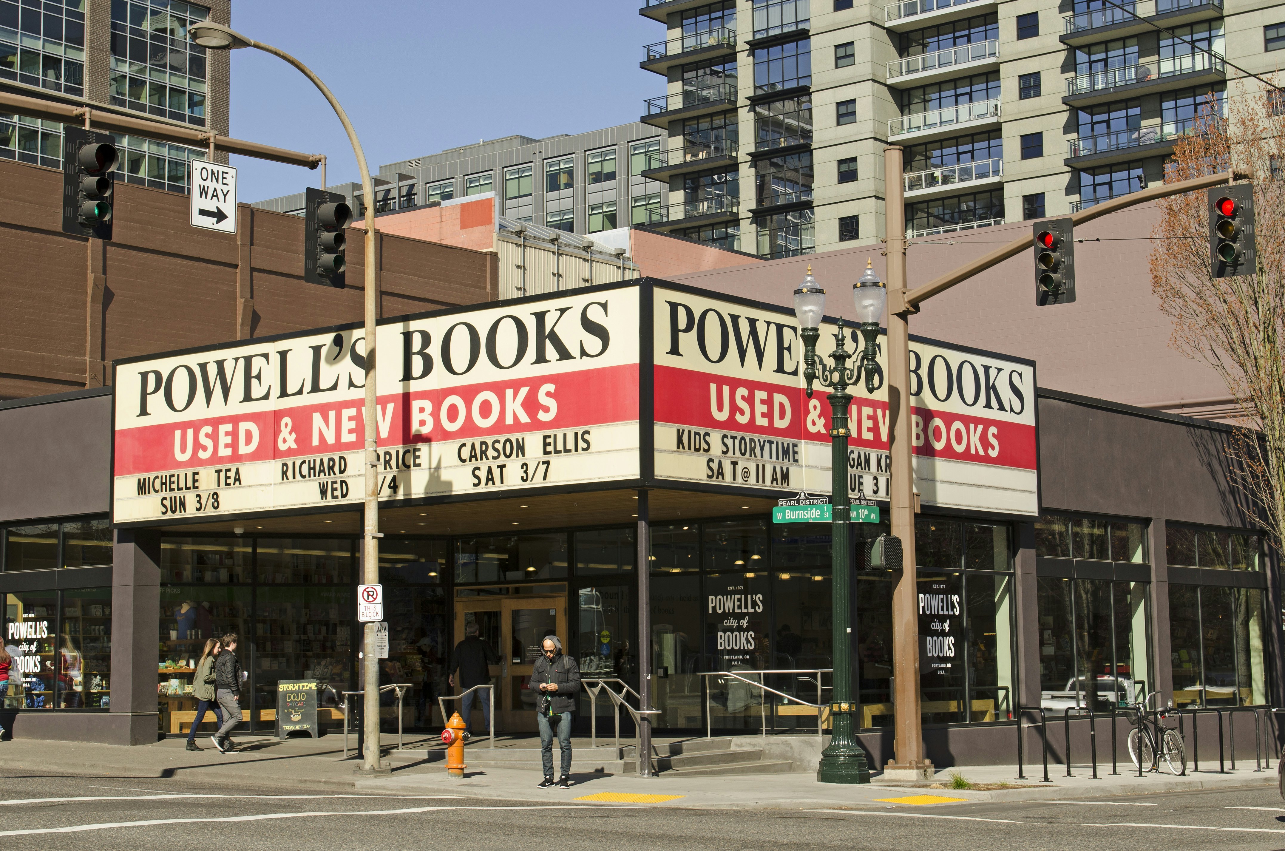 Exterior of a large bookstore with a huge sign that says "Powell's Books: used and new books" on the corner of two streets