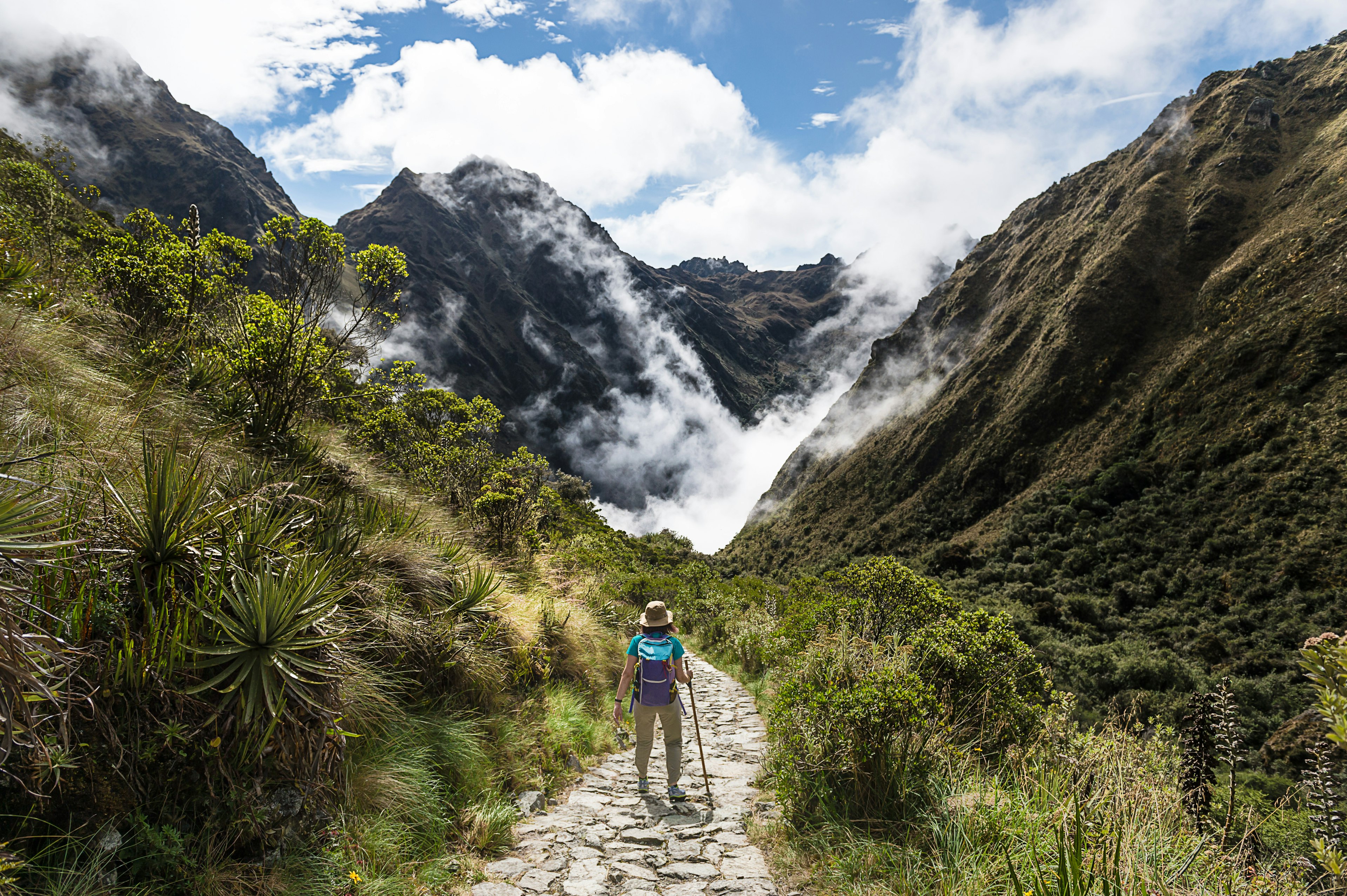 Female trekker walking through a misty valley on the Inca Trail.