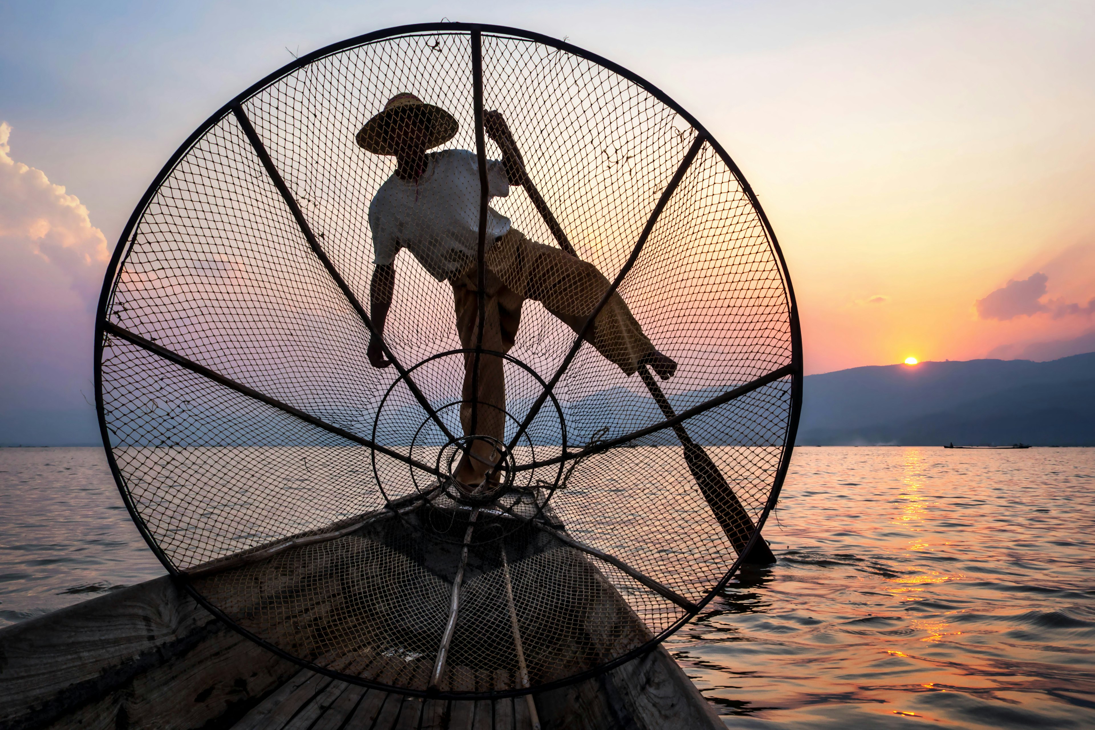 An Intha fisherman rowing at sunset.