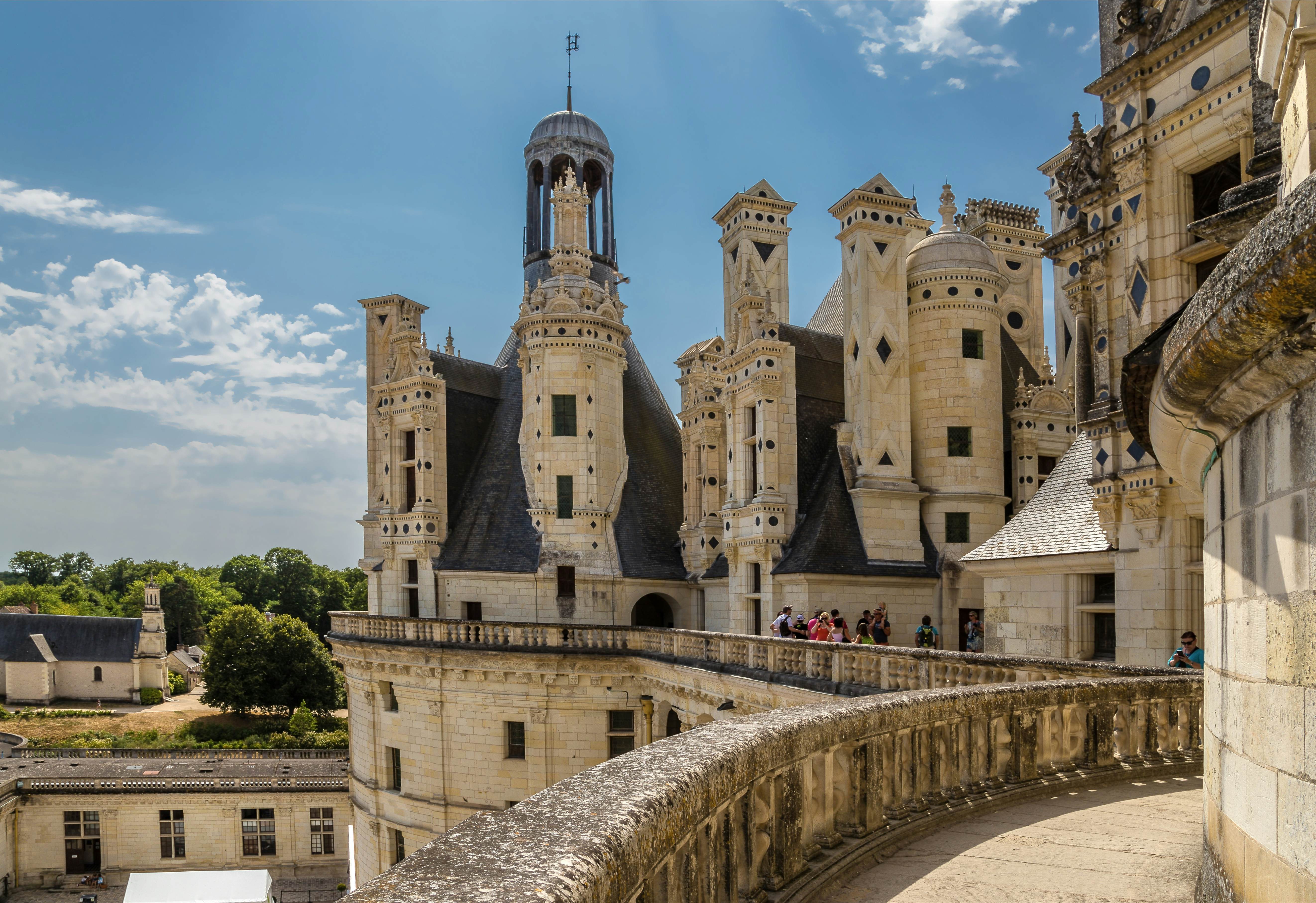 People stand on the balcony walkway of a beautiful chateau in France.