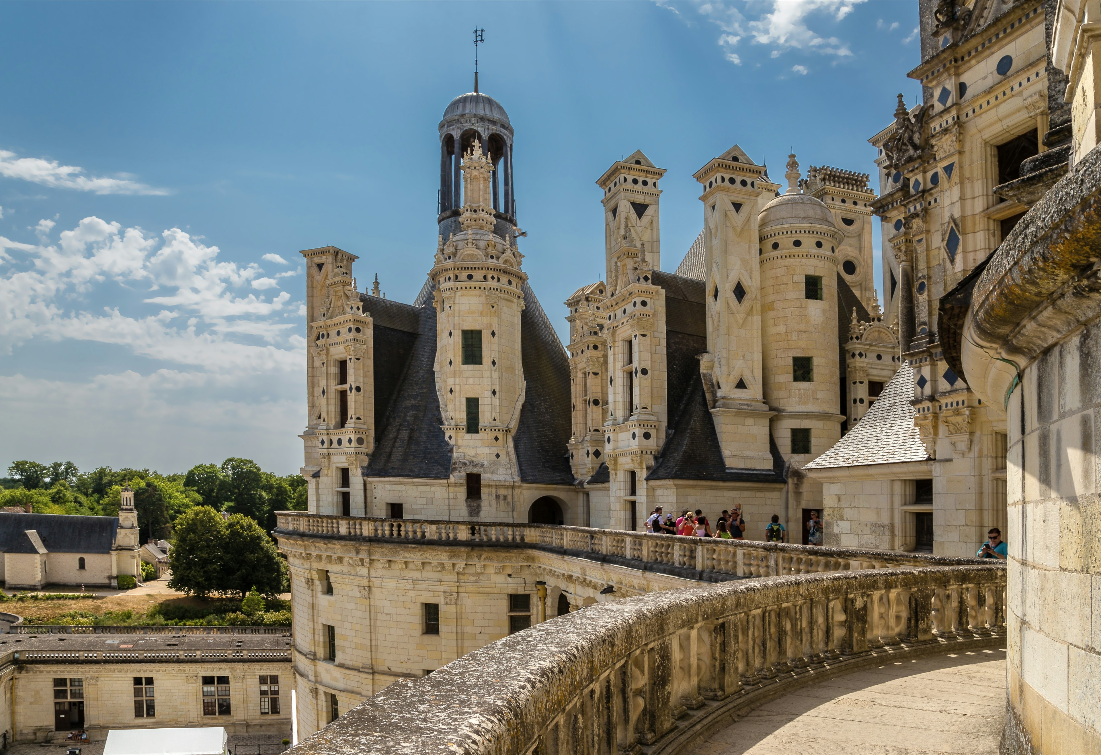 People stand on the balcony walkway of a beautiful chateau in France.