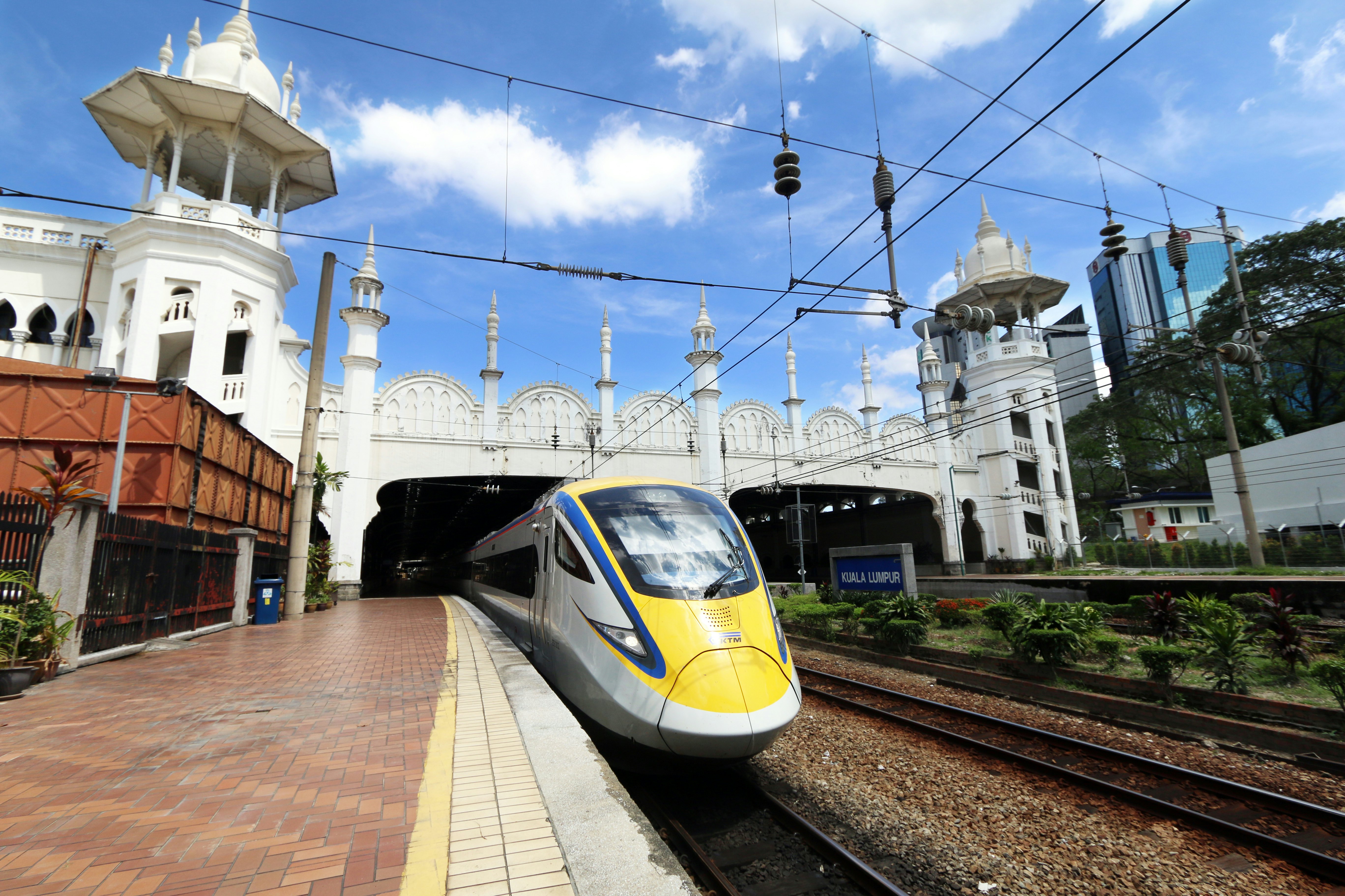 The yellow-painted front of a high-speed train emerges from a tunnel and next to a platform at the station at Kuala Lumpur, Malaysia