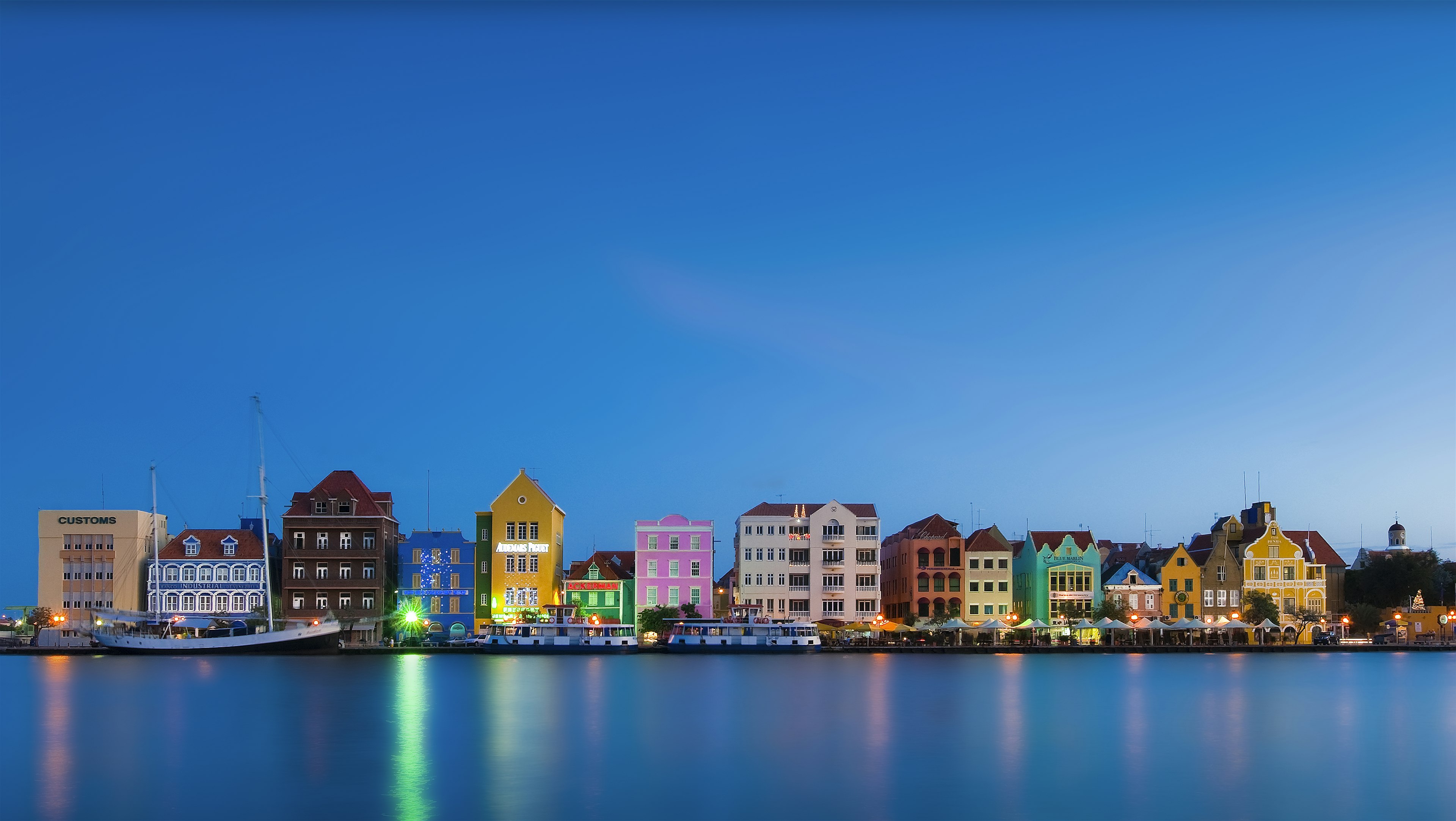 A series of pastel-colored buildings lining a waterfront lit up at night