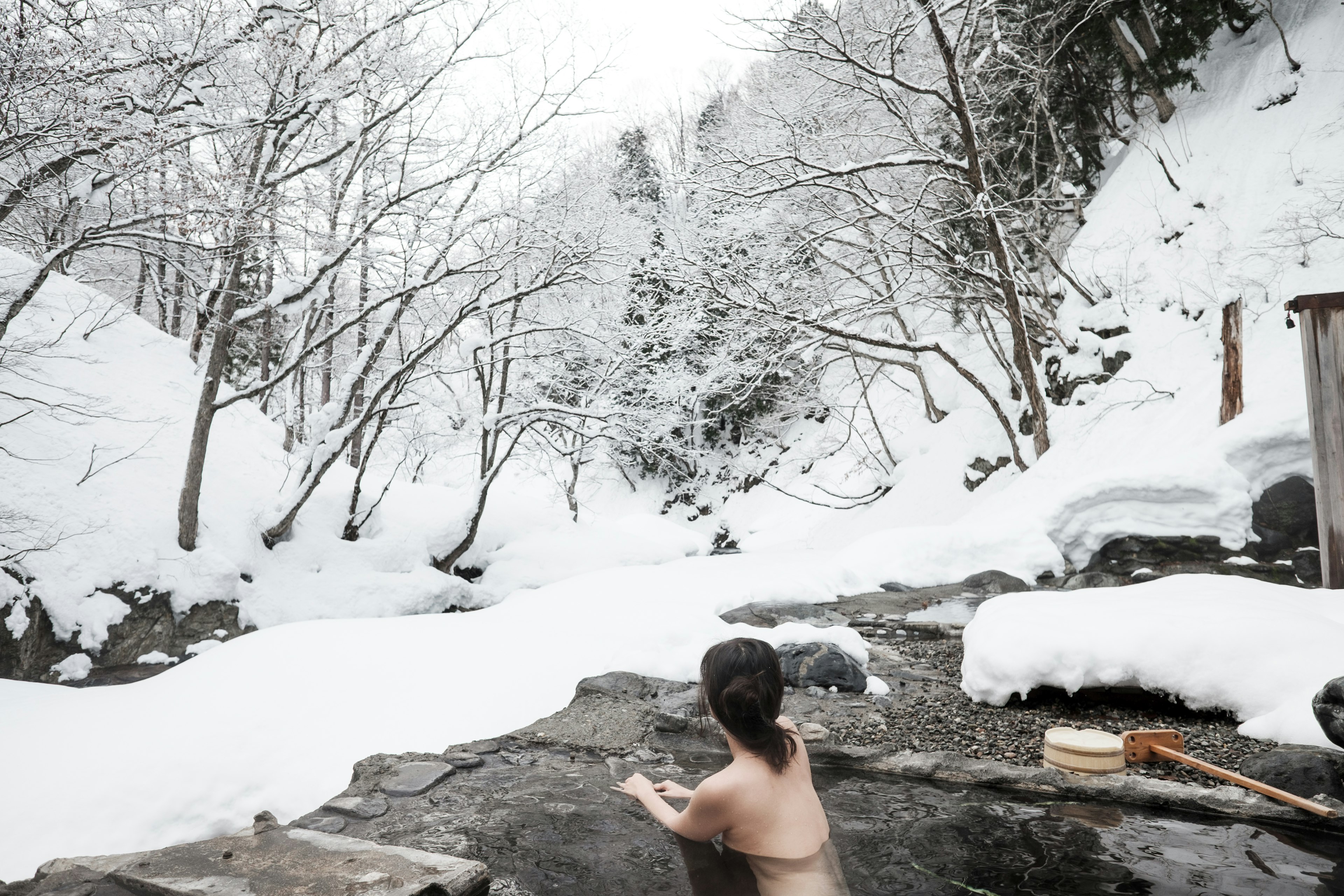 A woman relaxes in a snow covered mountain hot spring onsen resort in Japan.