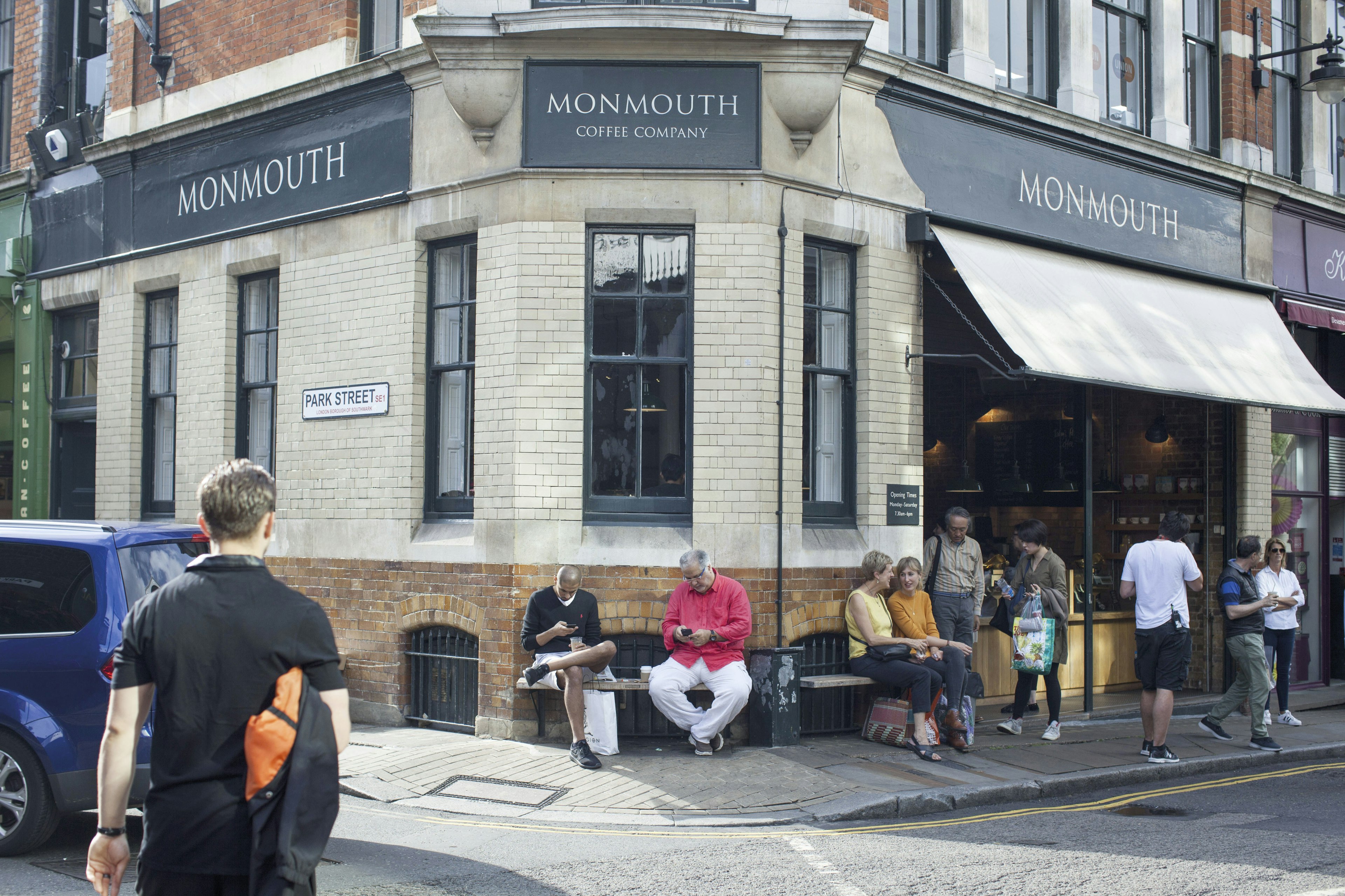 People are seated out the front of Monmouth Coffee Company.