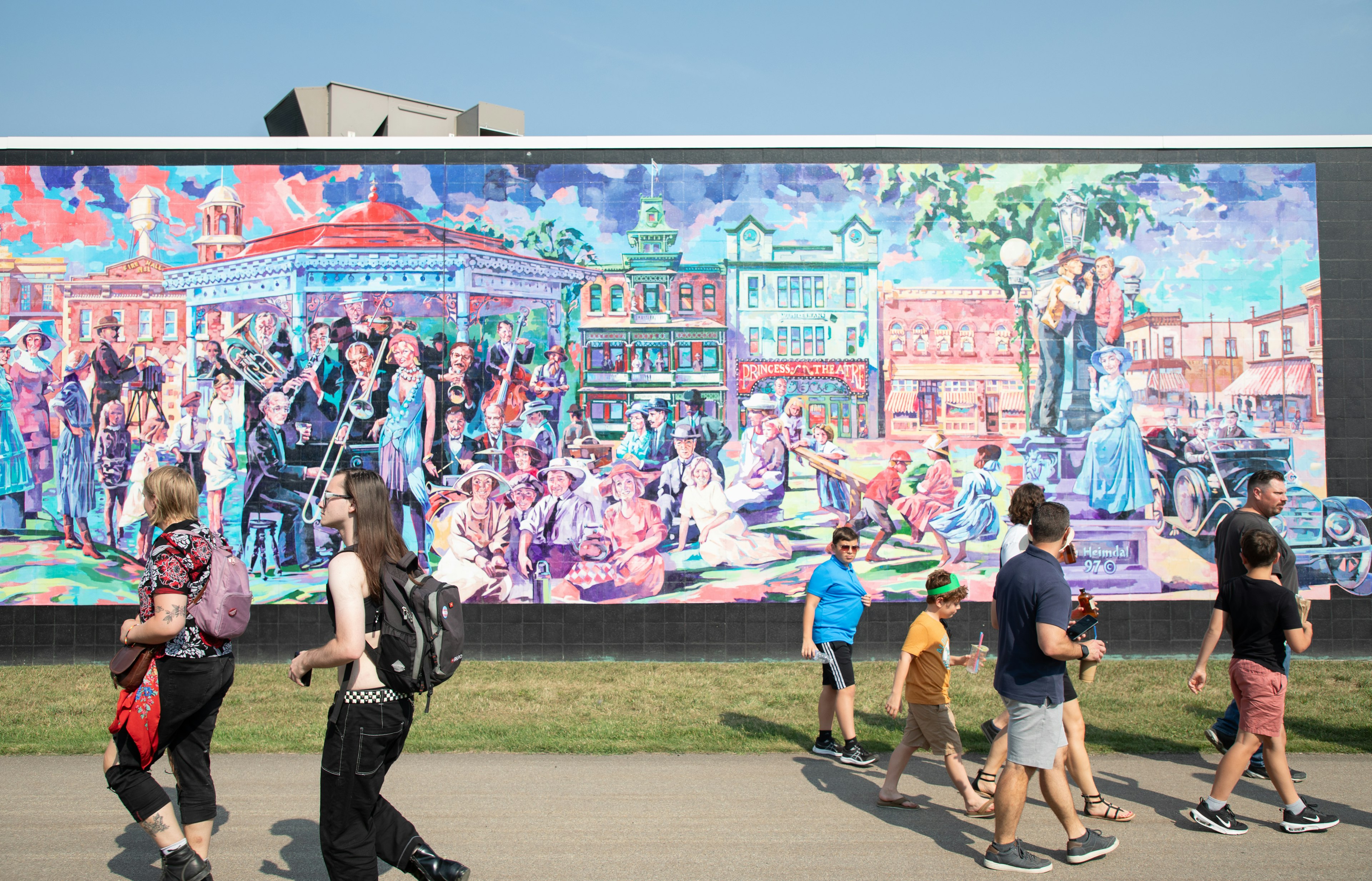 People walk past a colorful mural in the Whyte Avenue area in Edmonton, Alberta.