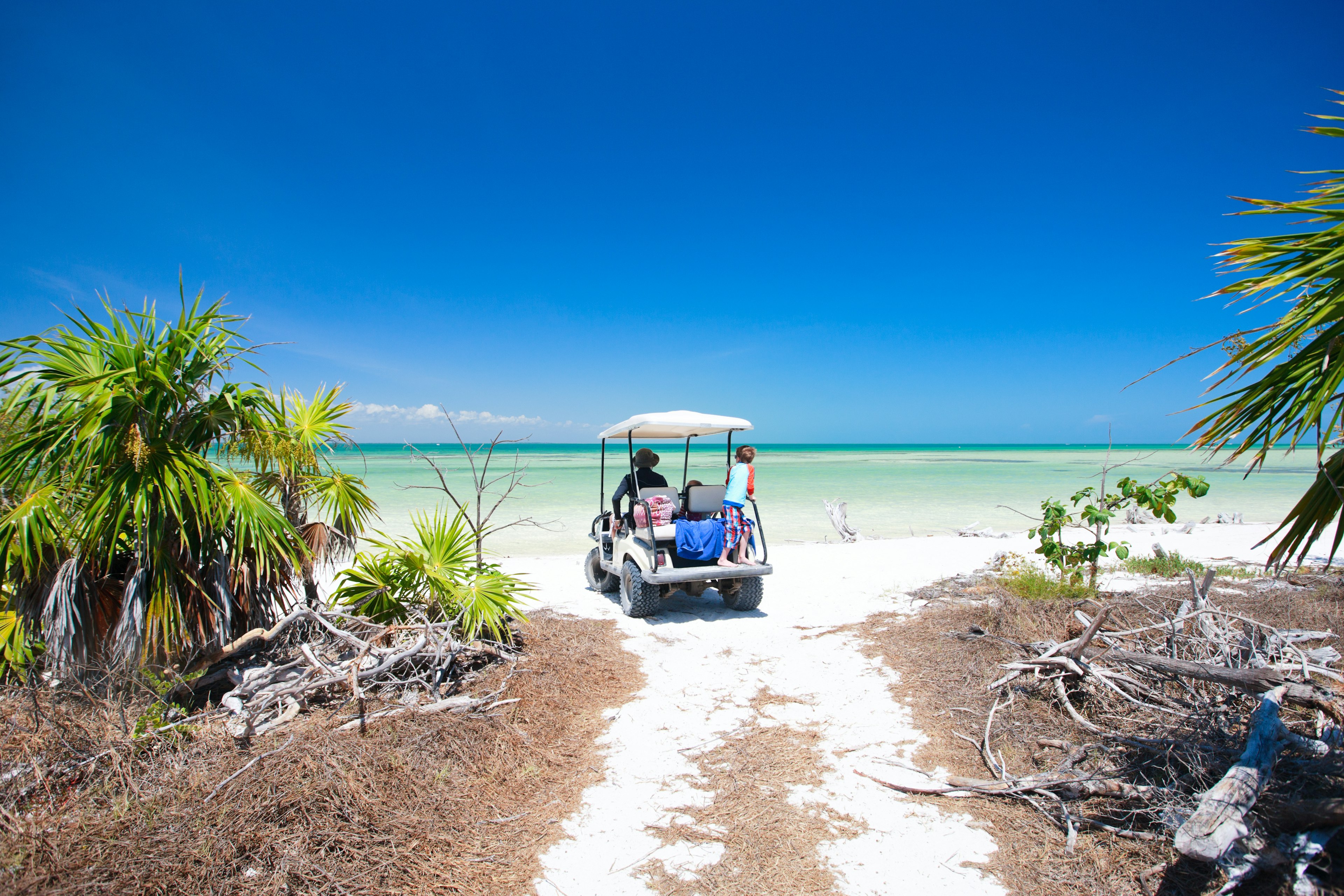 A family driving in golf cart along the tropical beach of Isla Holbox, Mexico