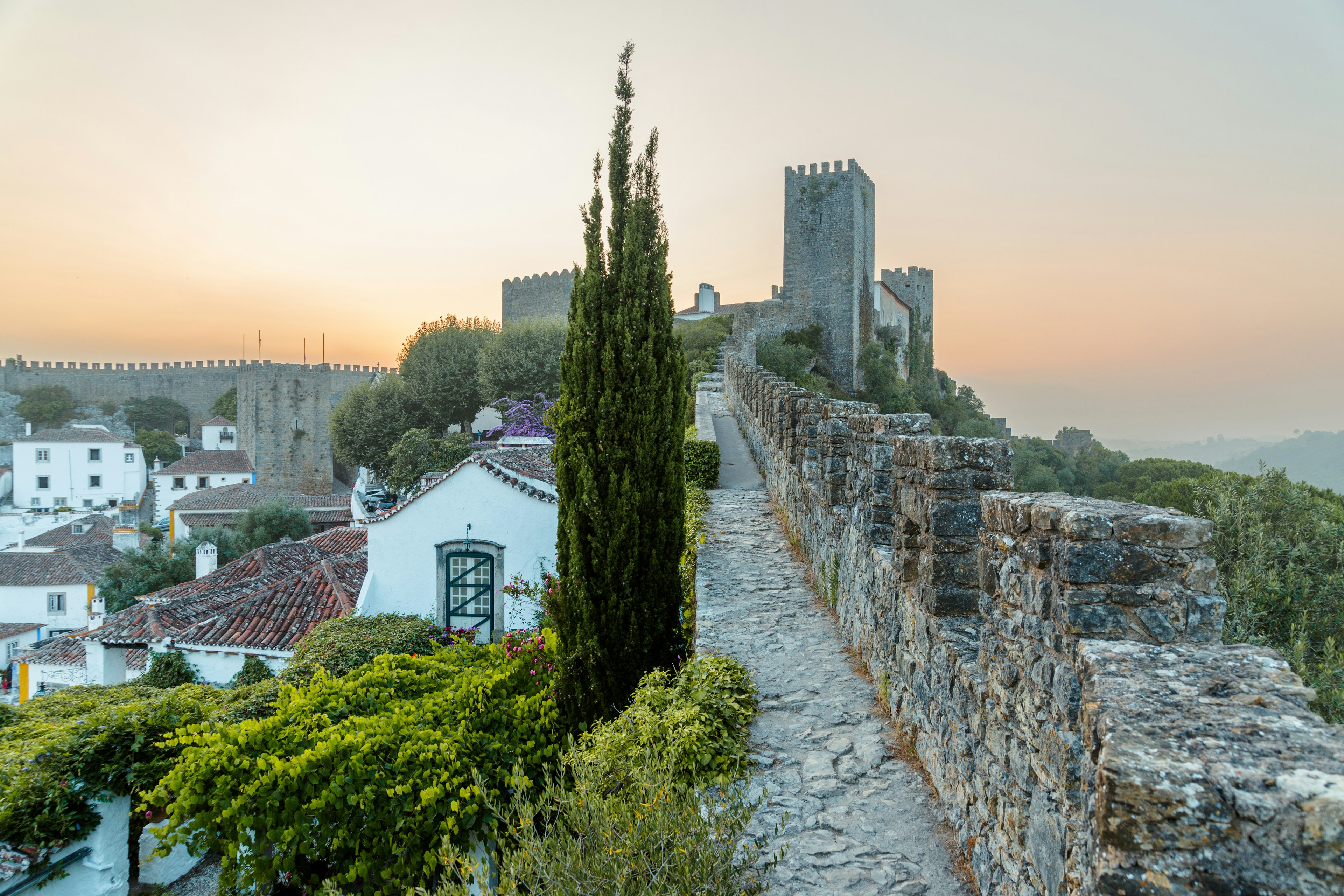 The fortified walls of an old town bathed in light as the sun sets