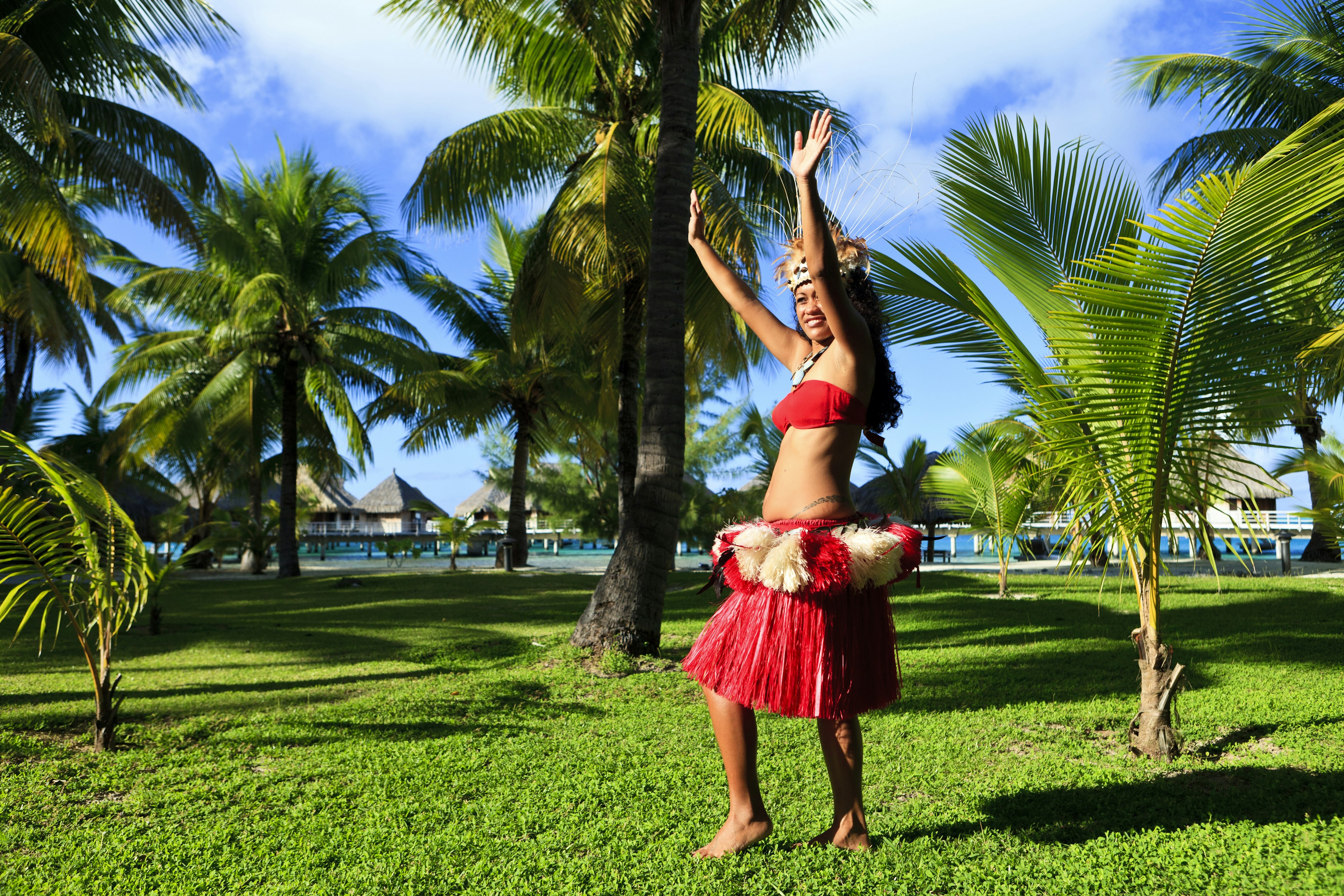 Woman dancing in traditional costume surrounded by palm trees, Bora Bora.