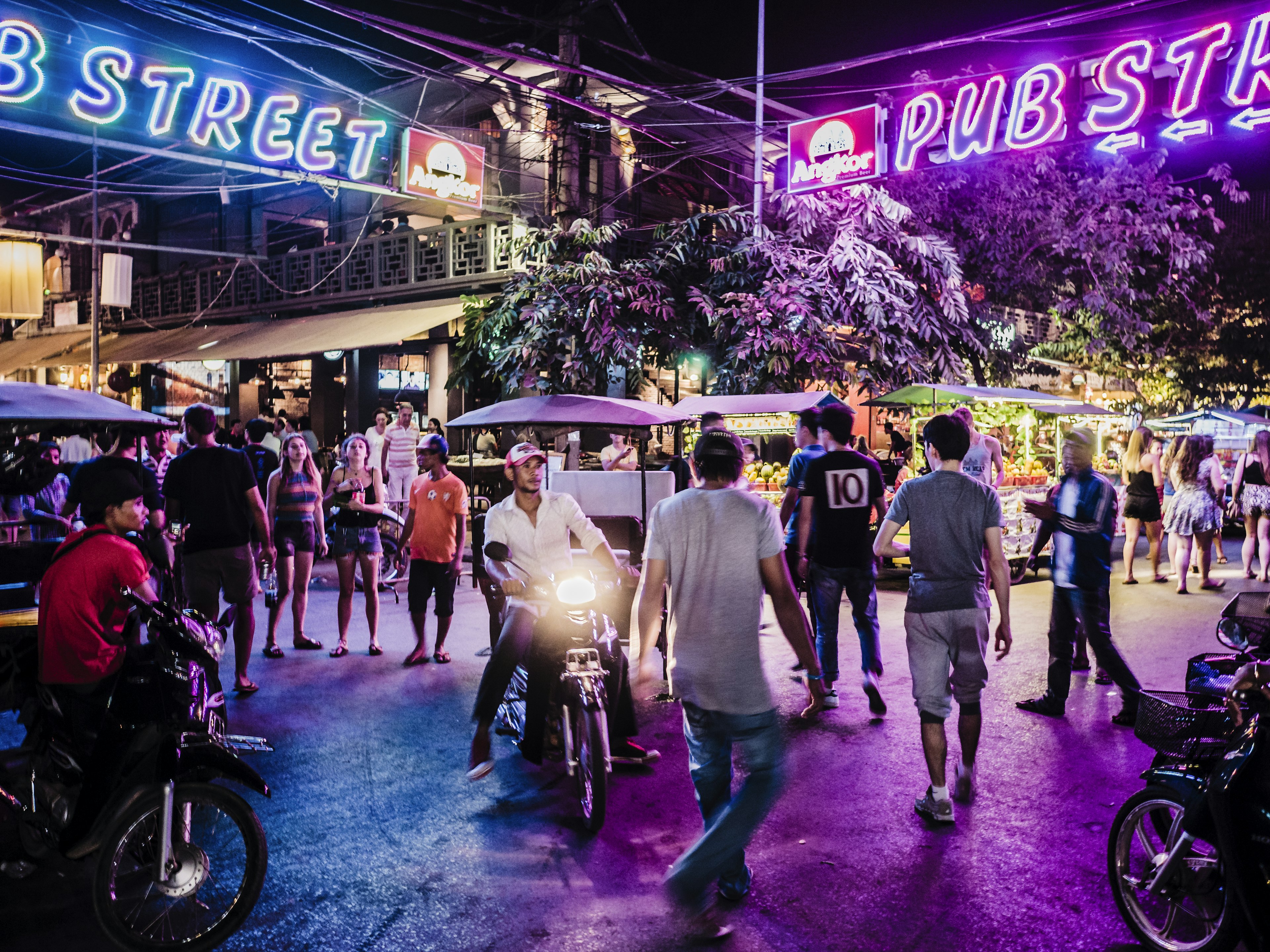 People under neon lights at Pub Street at night in Siem Reap, Cambodia.