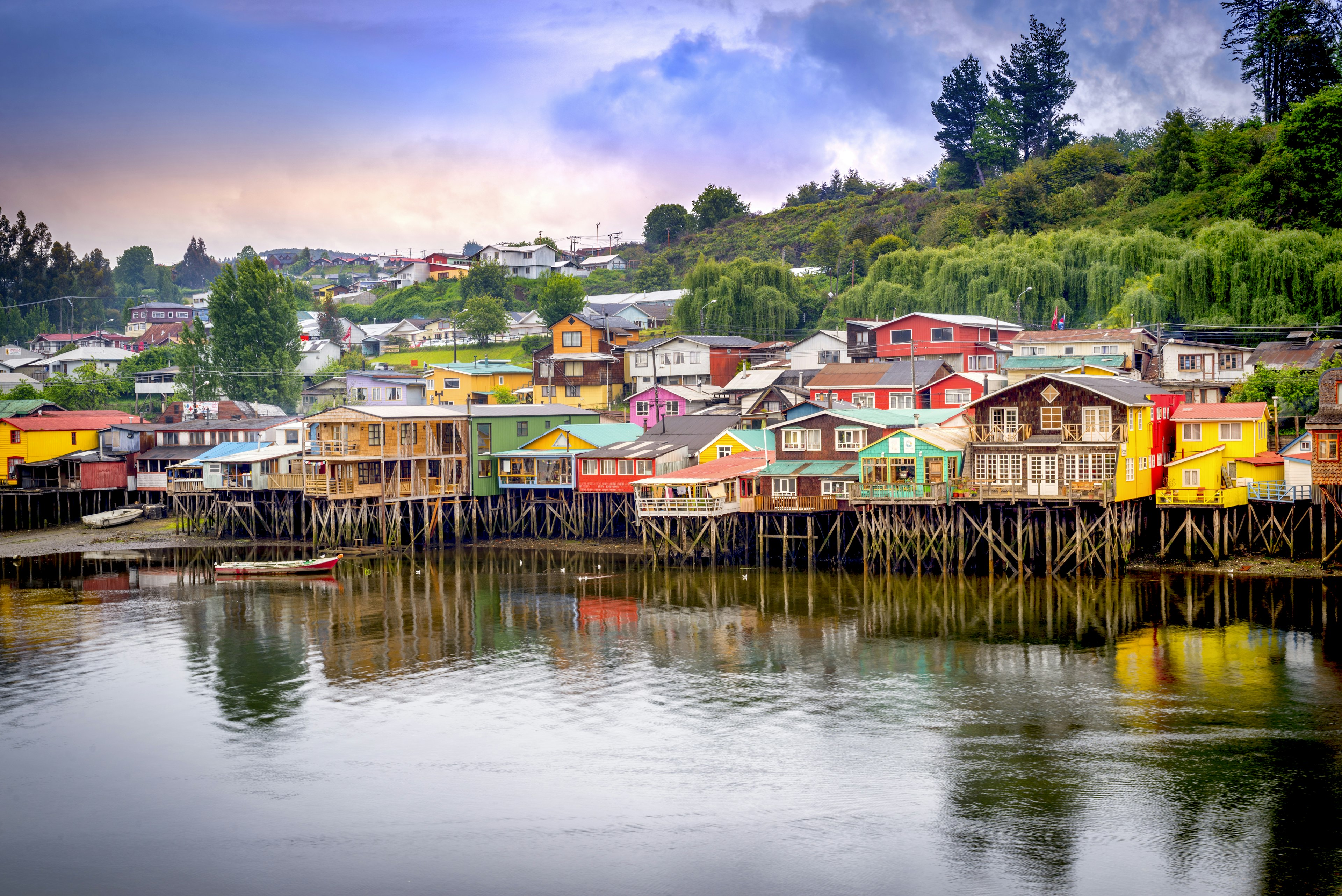 Wooden stilt houses line a waterway painted in bright colors