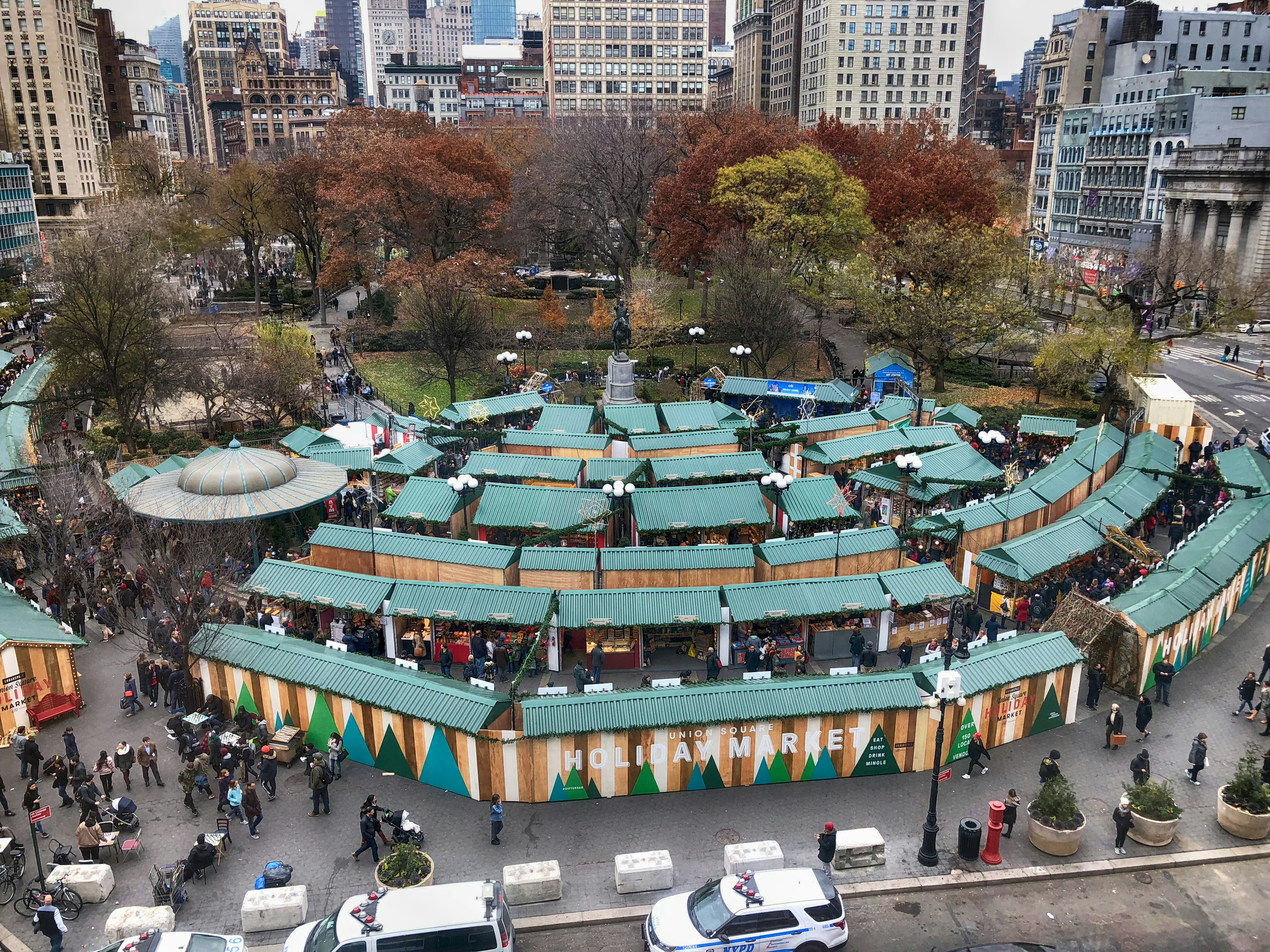 A series of wooden stalls form a festive market in a city park