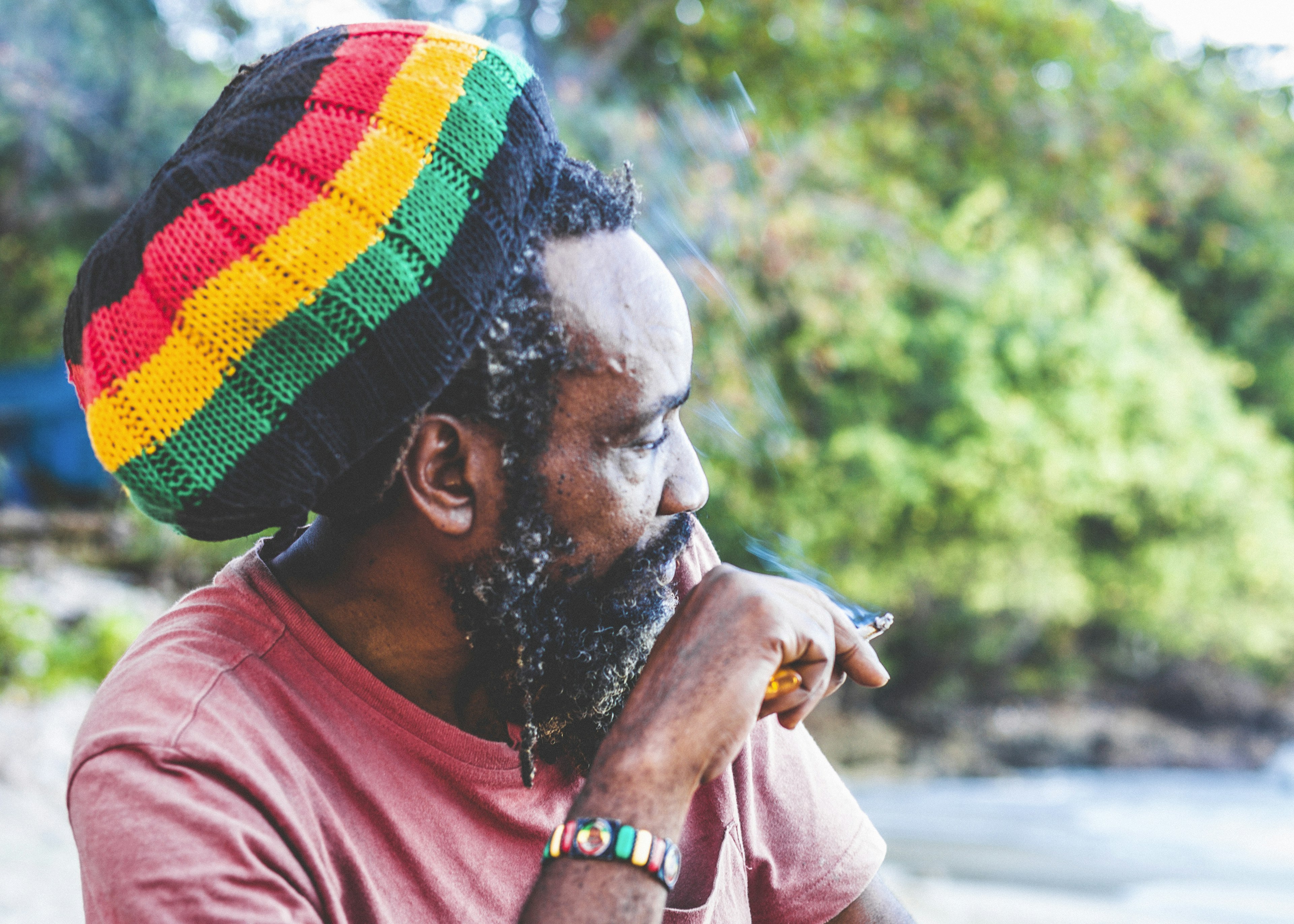 Senior Rastafarian man smoking at the beach.