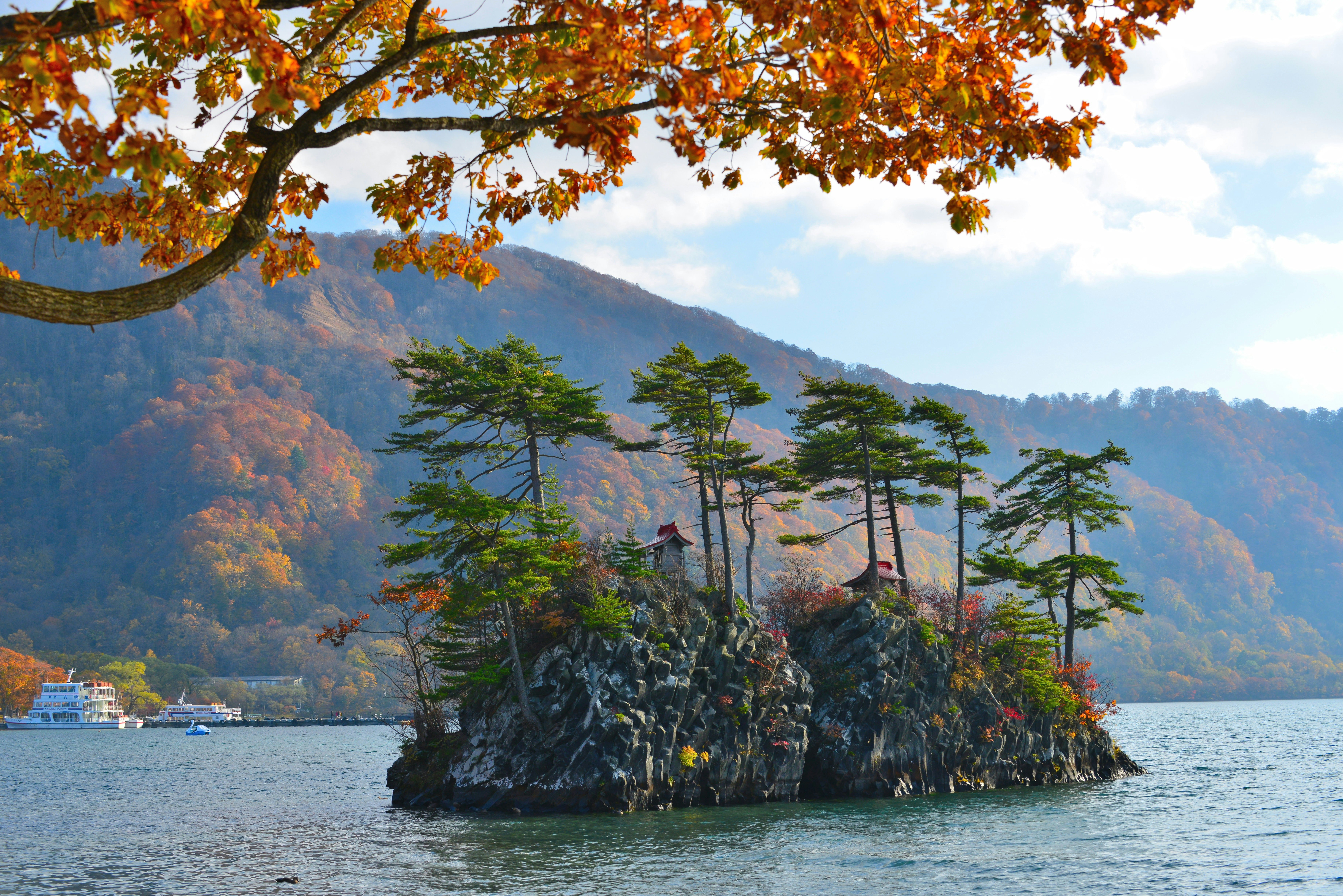 Two rocky outcrops covered in trees in the middle of a still lake.