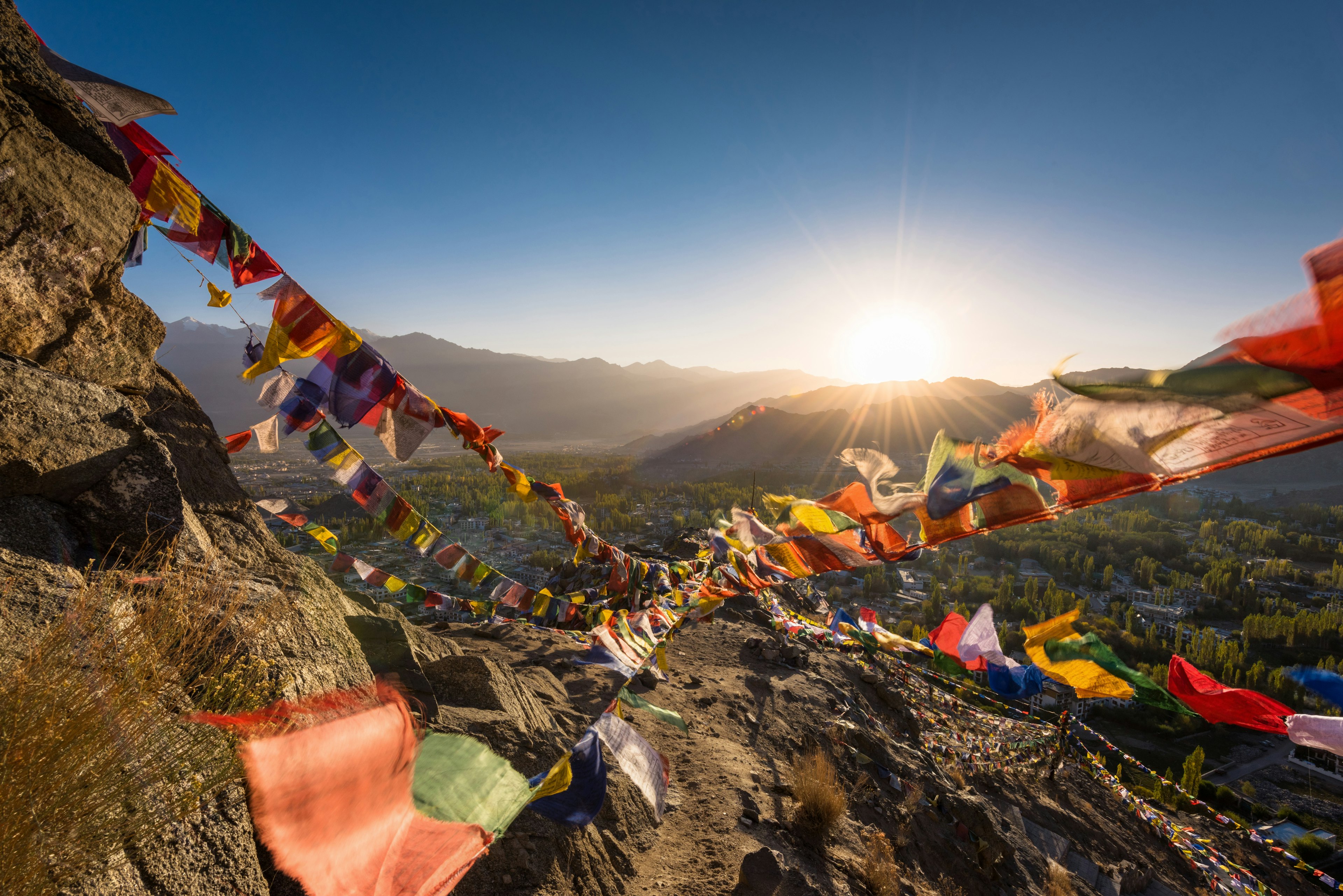 Colourful Buddhist prayer flags flutter in the breeze as the sun rises over mountains