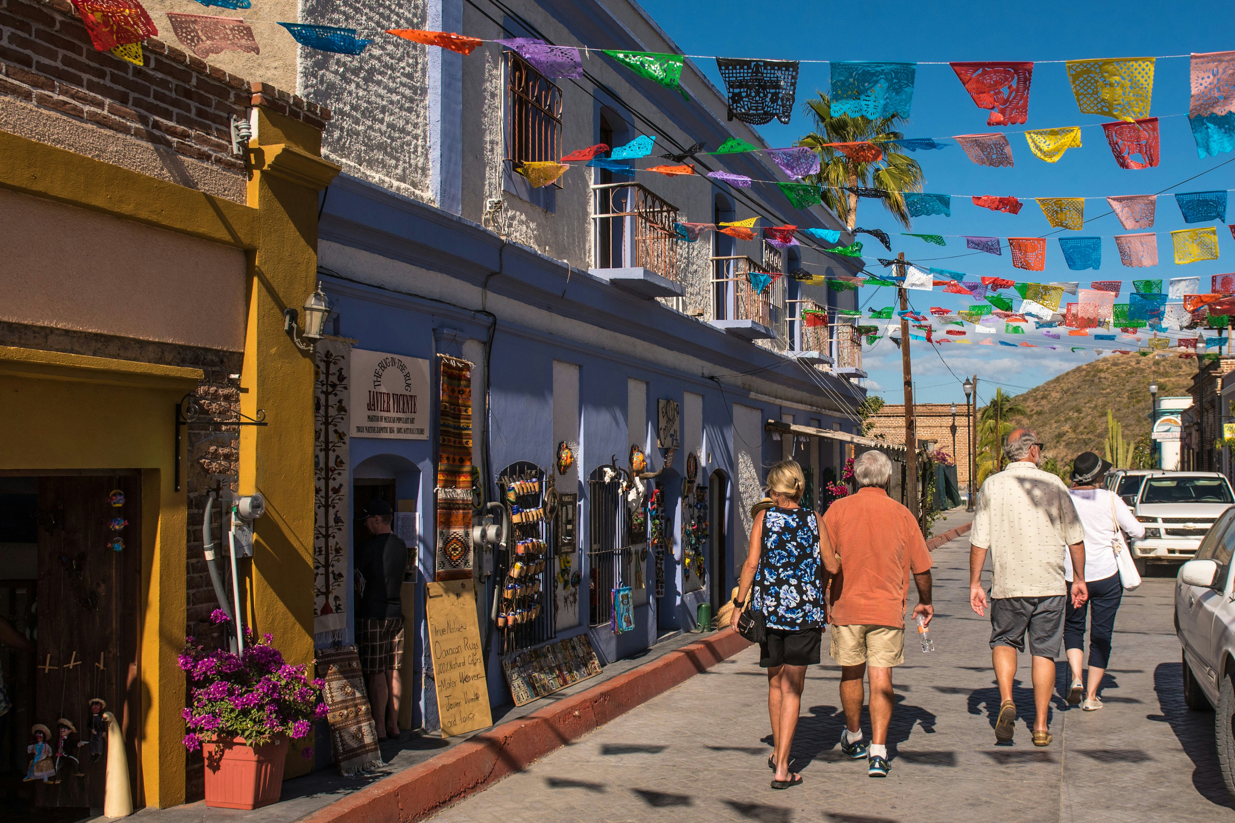 A couple walk along a flag-draped street in Todos Santos.