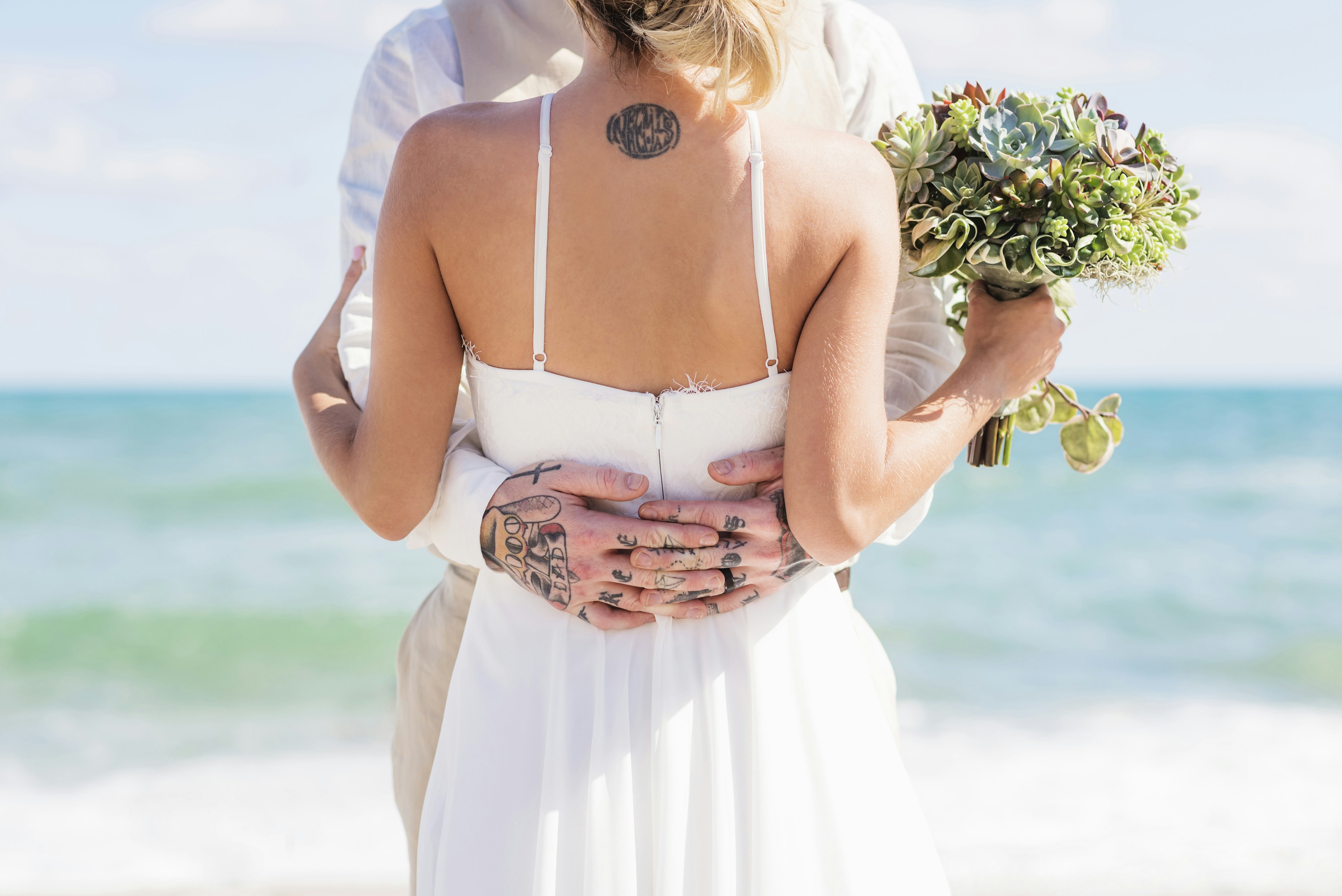 A newly married couple hug on the beach.