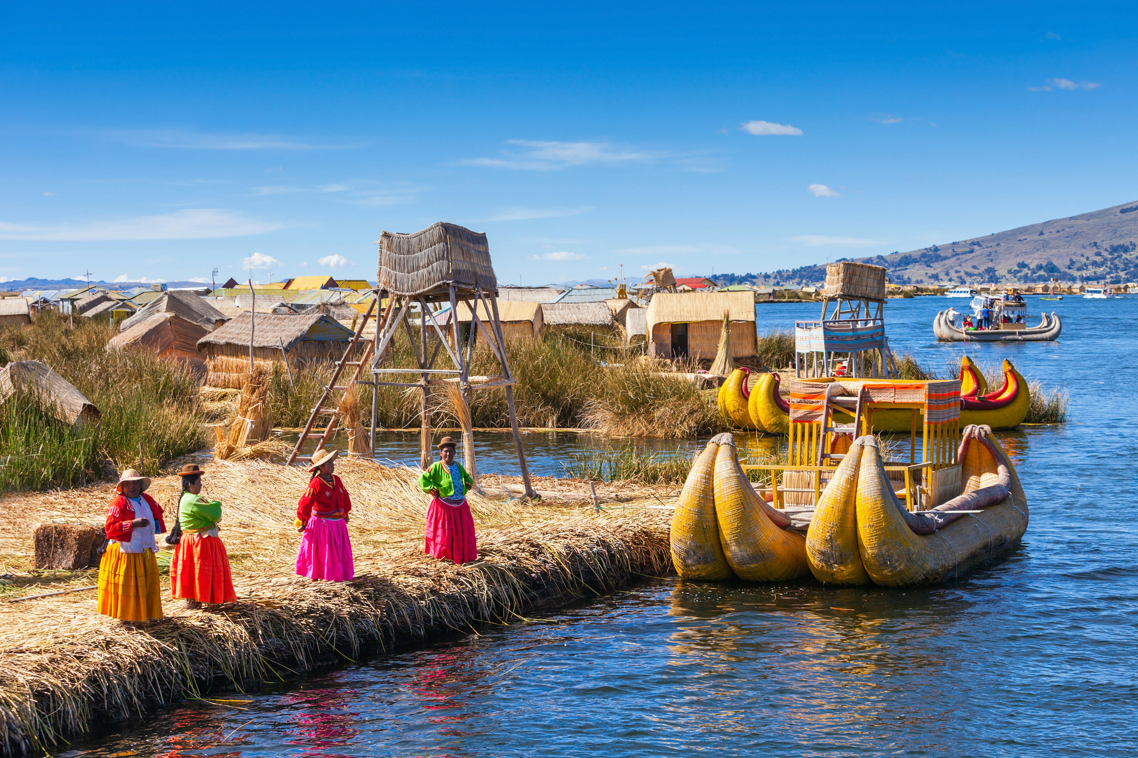 Unidentified women in traditional dresses welcome tourists in Uros Island.