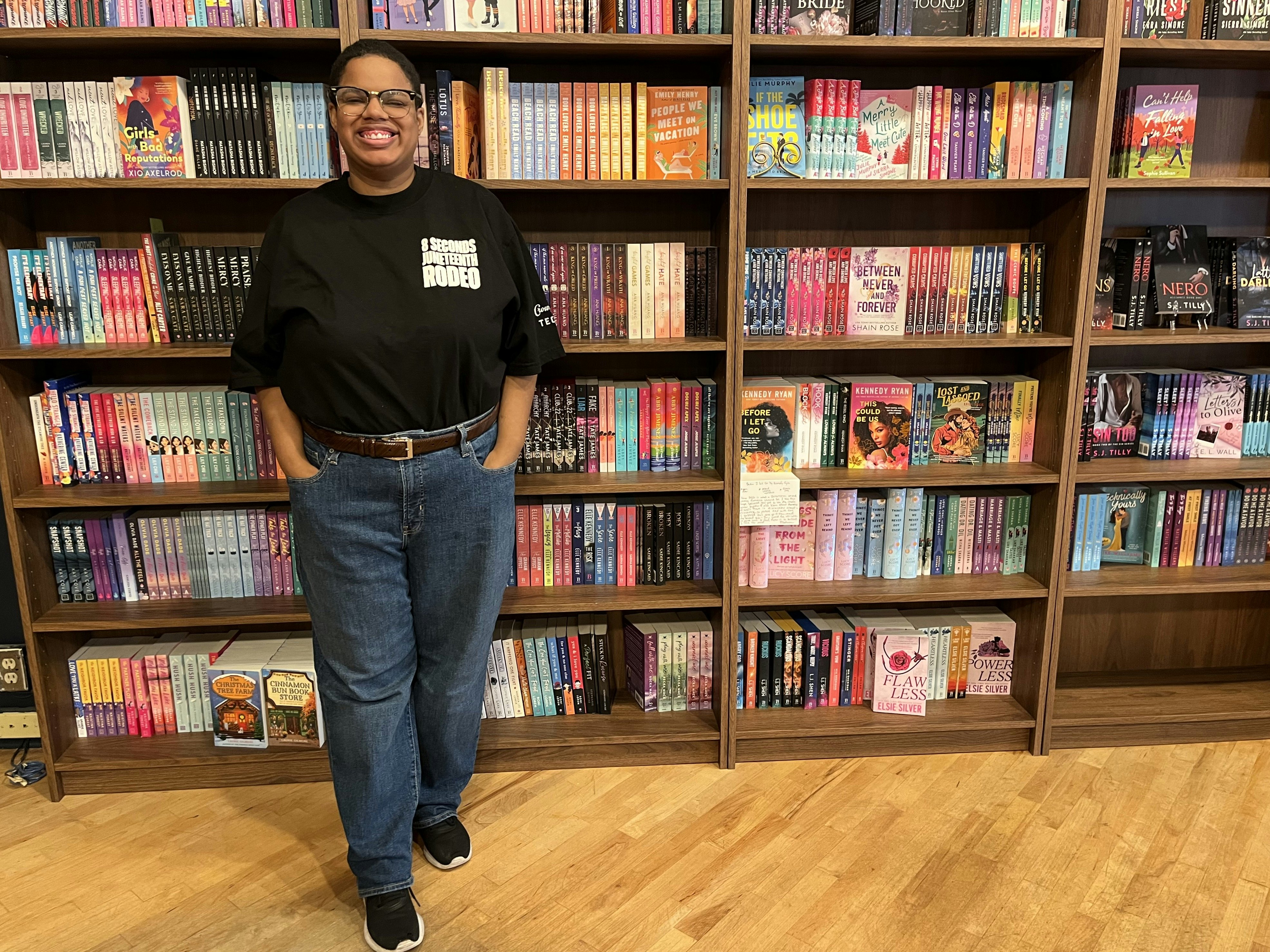 Owner Katherine Morgan stands in front of a bookcase whose shelves are packed with books at romance-book store Grand Gesture in Portland, OR