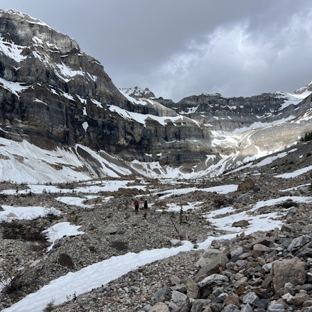 Hikers follow a trail through a snowy valley
