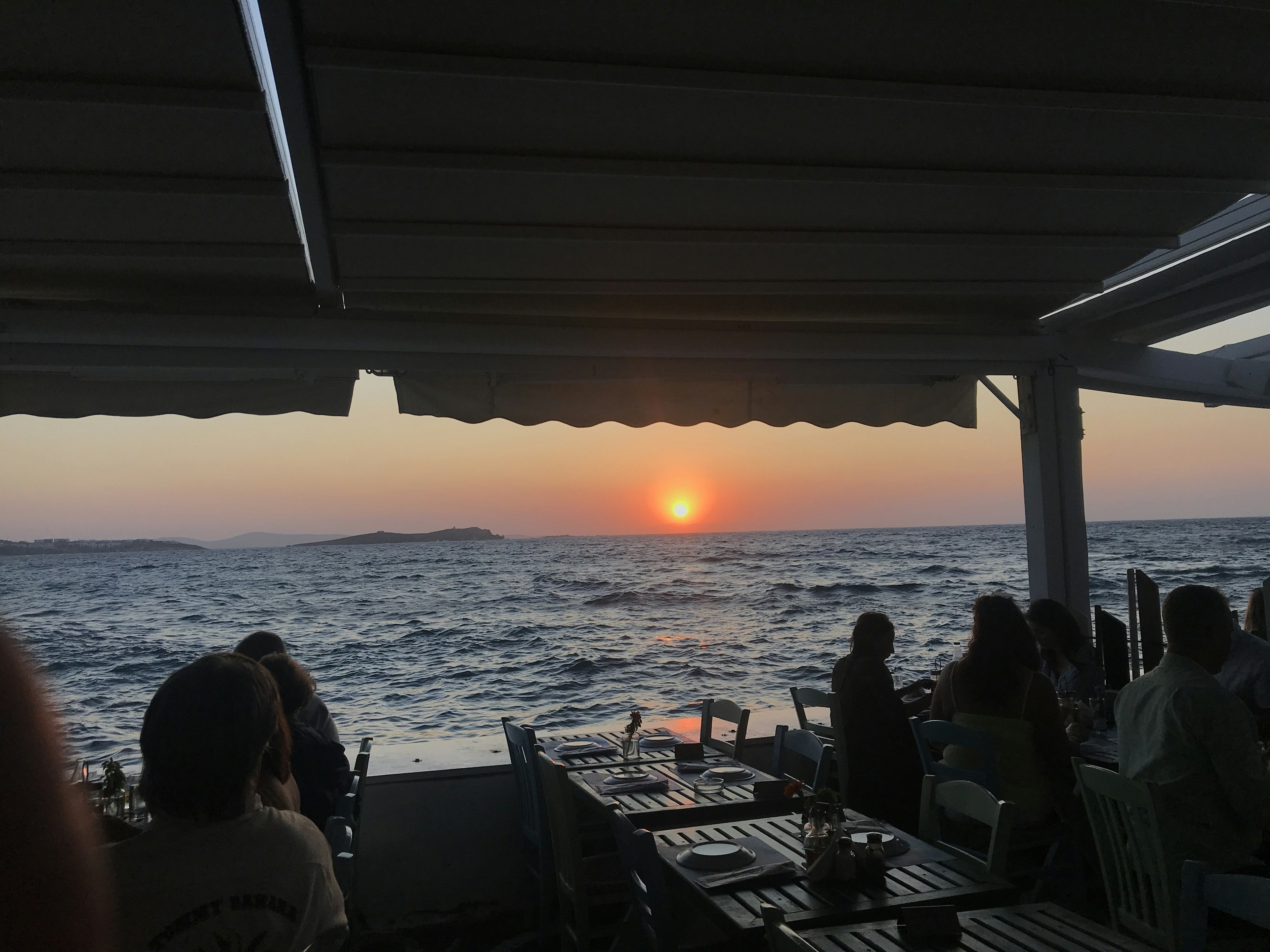 A sunset over sea viewed from a restaurant terrace