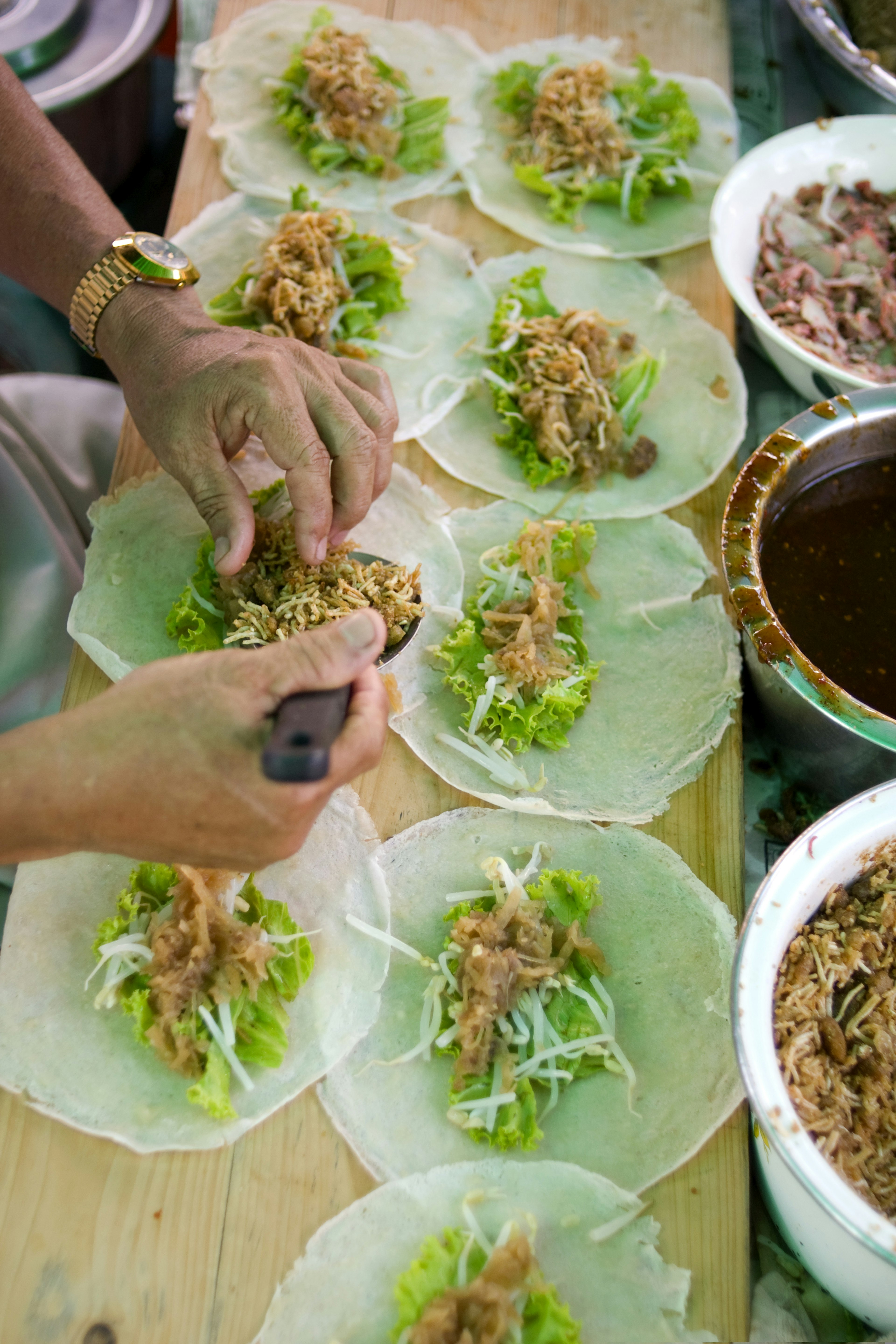 A vendor prepares spring rolls at a food stall in Phuket