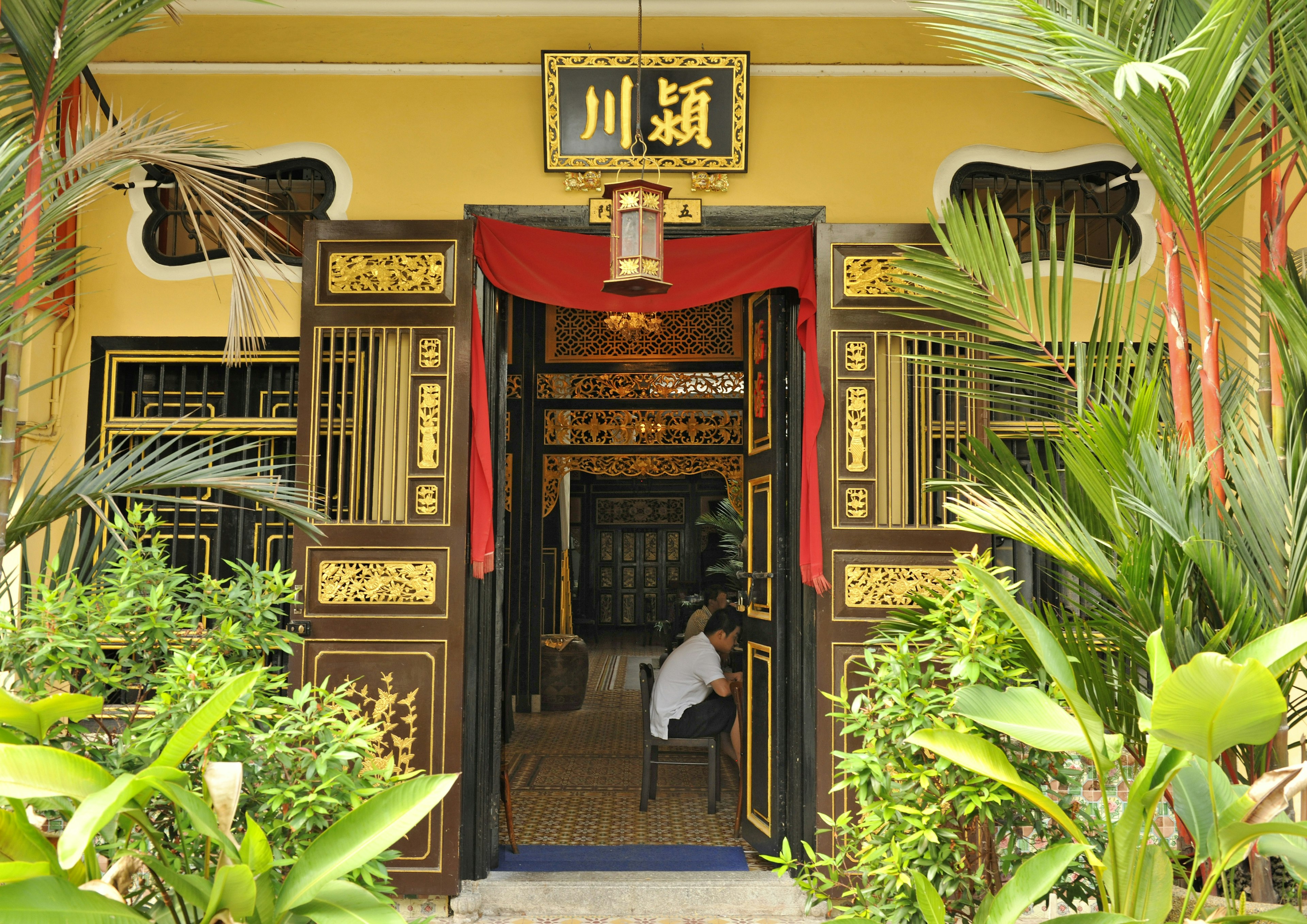 A doorway surrounded by ornate detail in gold leading to a small coffee shop